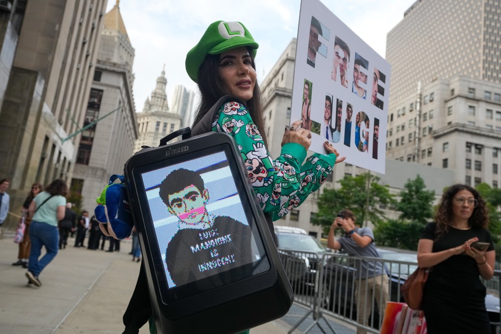 Woman in Luigi costume protesting outside a courthouse.
