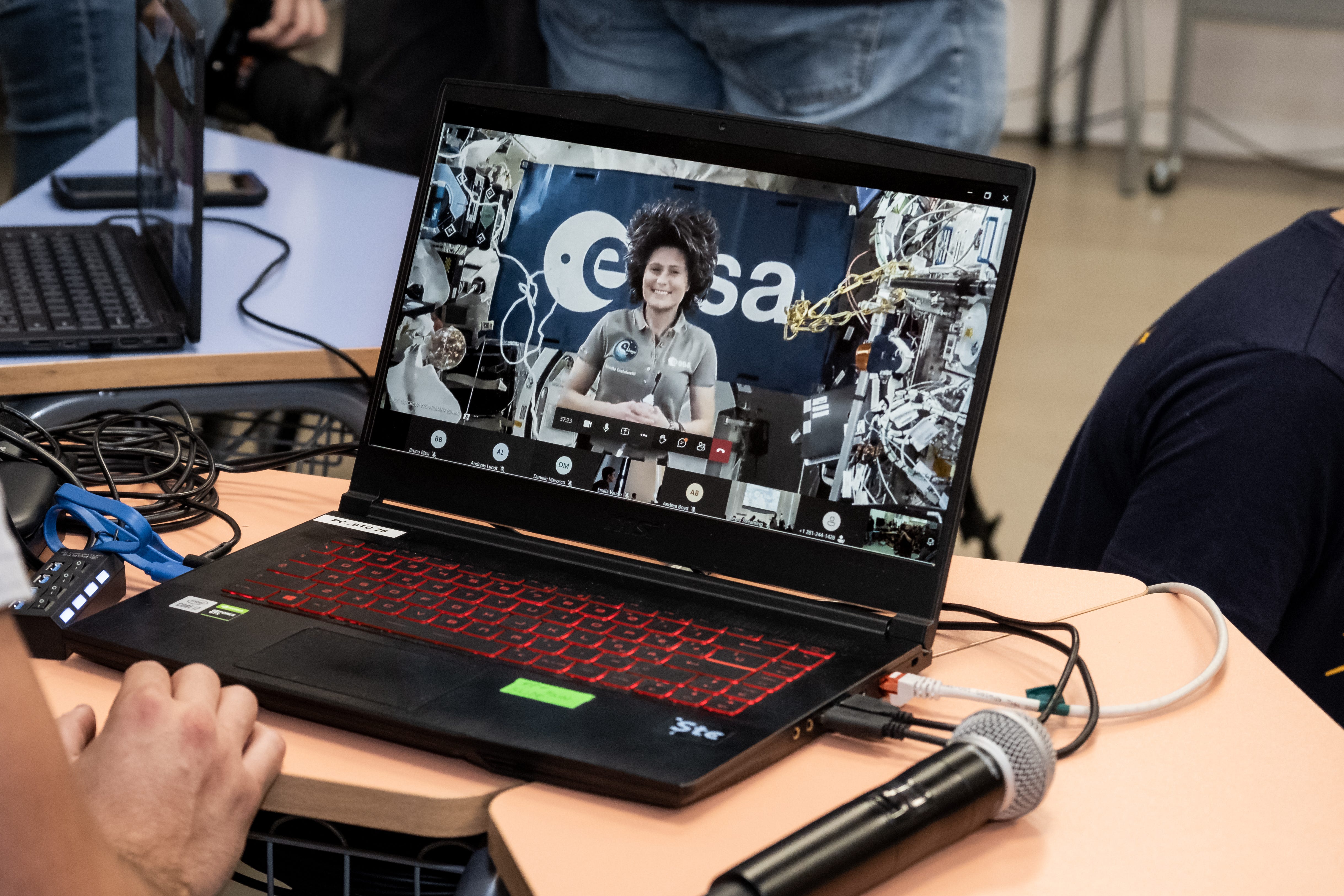 A laptop shows an astronaut on the ISS with the ESA logo behind her