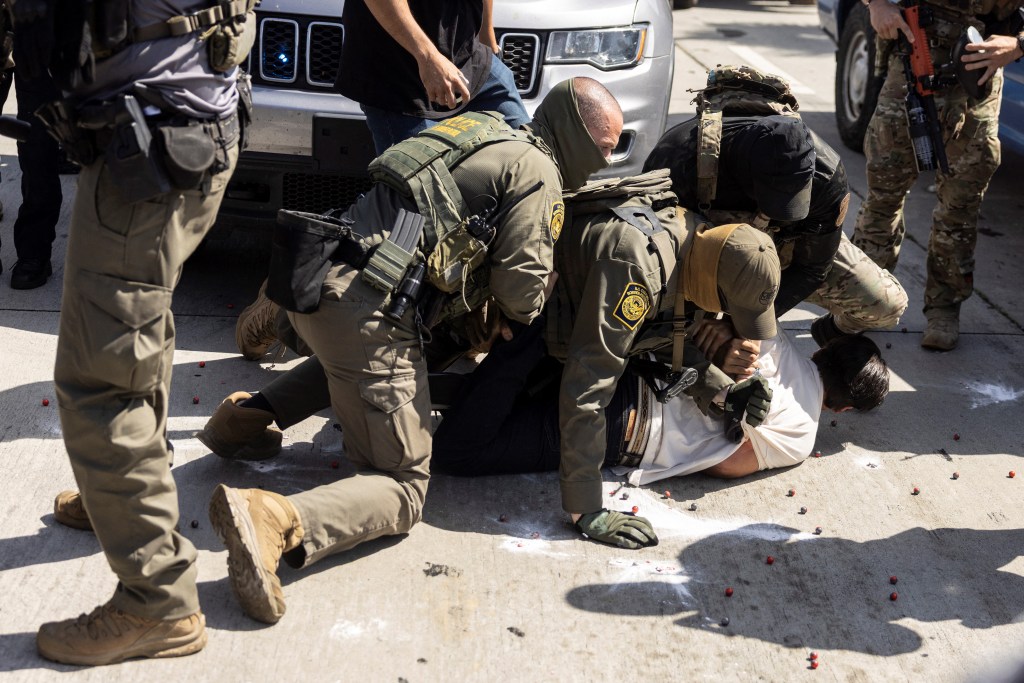 Law enforcement officers arresting a man on the ground.