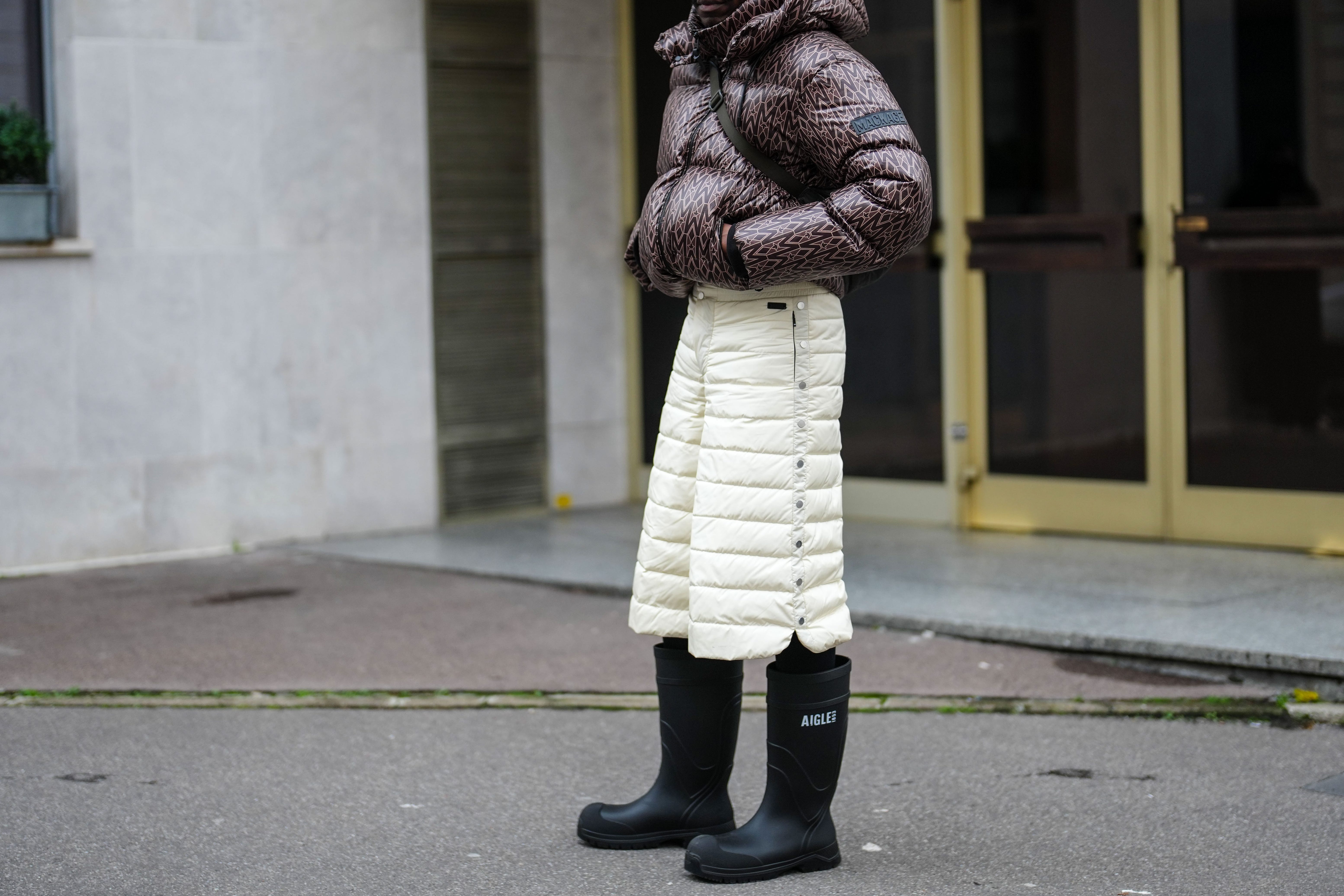 Person in hat wearing cropped, patterned puffer jacket and puff pants with boots