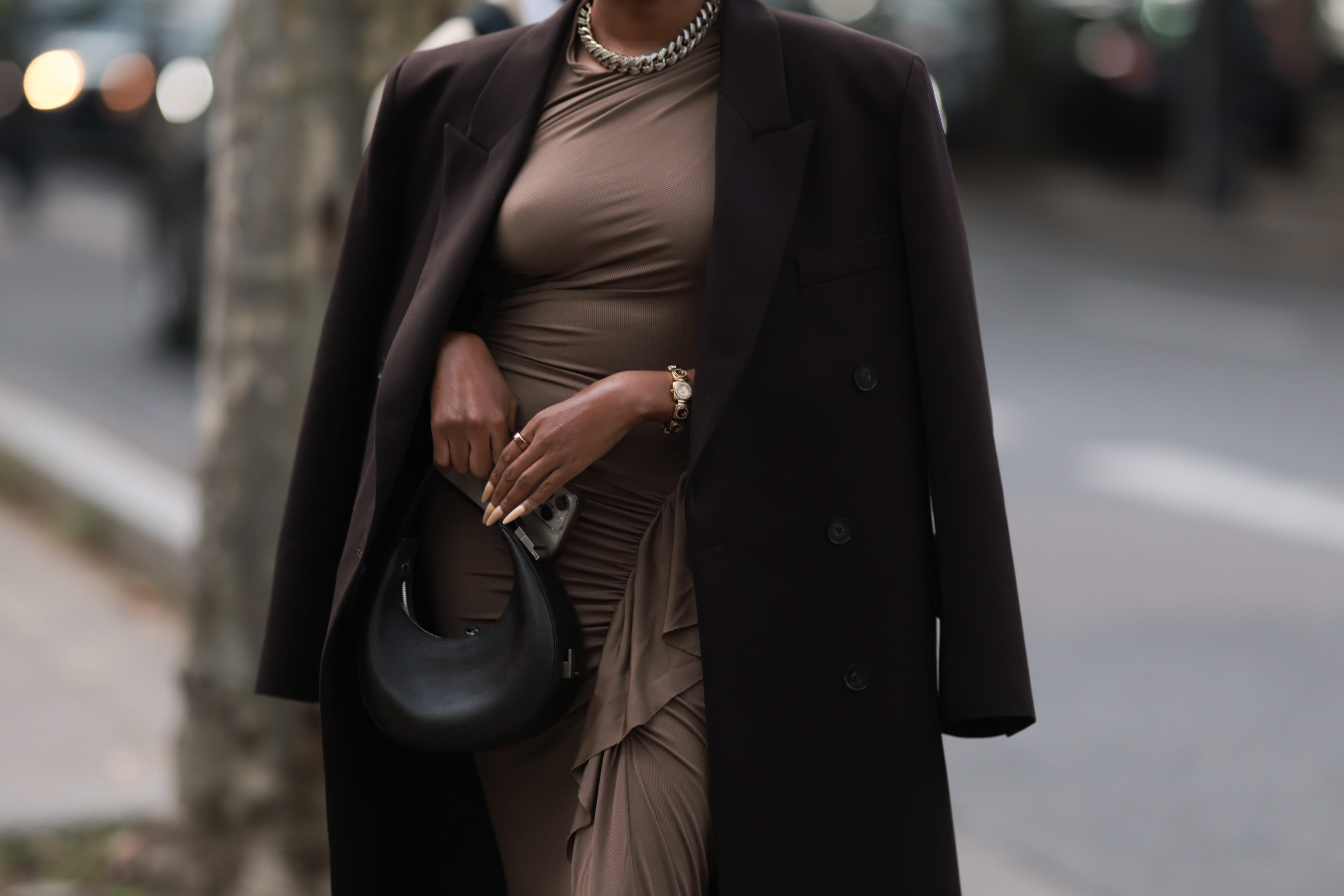 Woman with coat over shoulders holding small leather purse