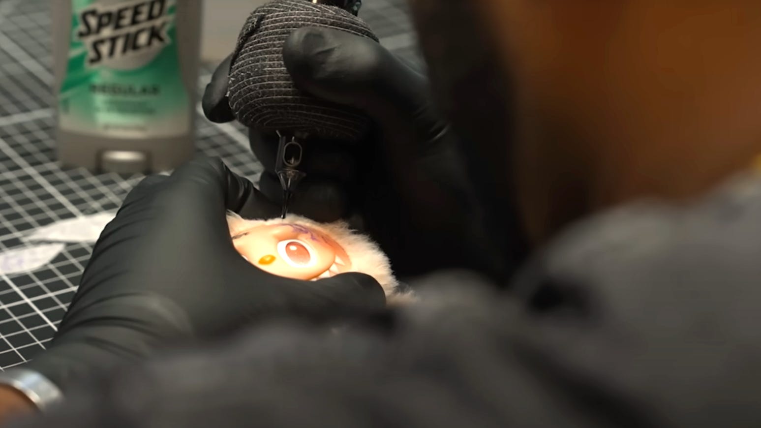 A man tatooing the face of a Labubu.