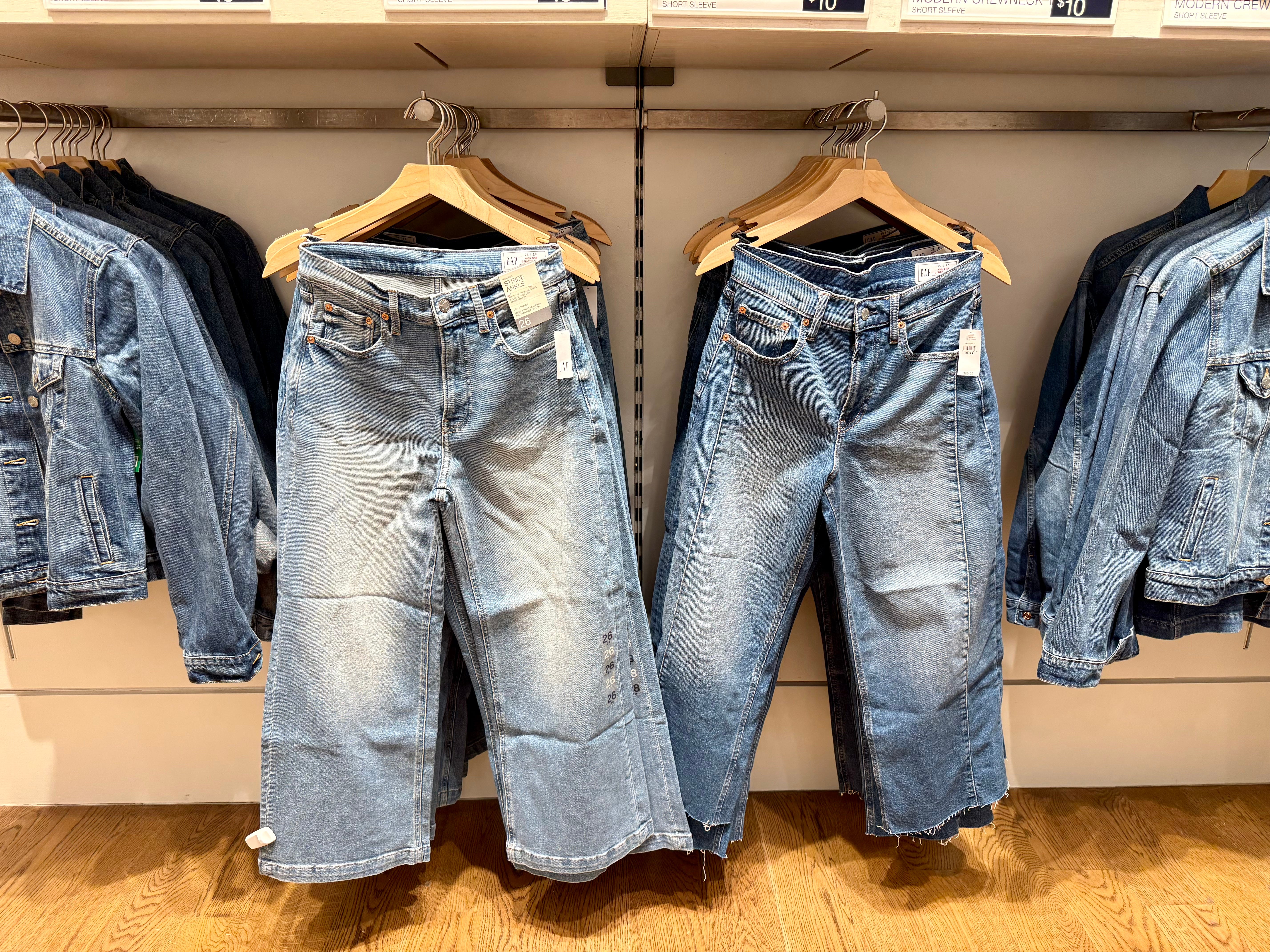 Mid-rise stride wide jeans hanging on hangers next to denim jackets at Gap