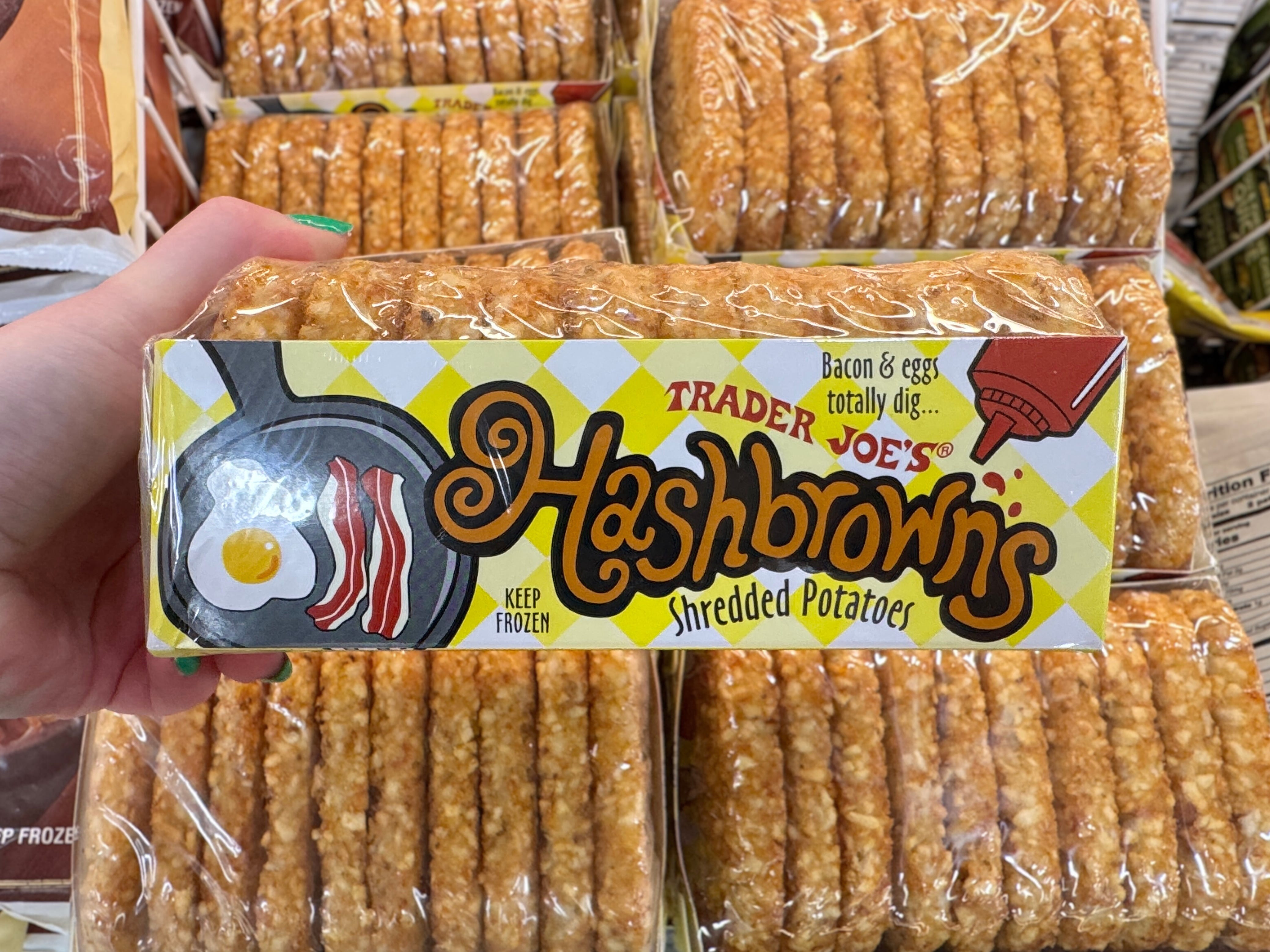 A hand holding a package of Trader Joe's hash browns.