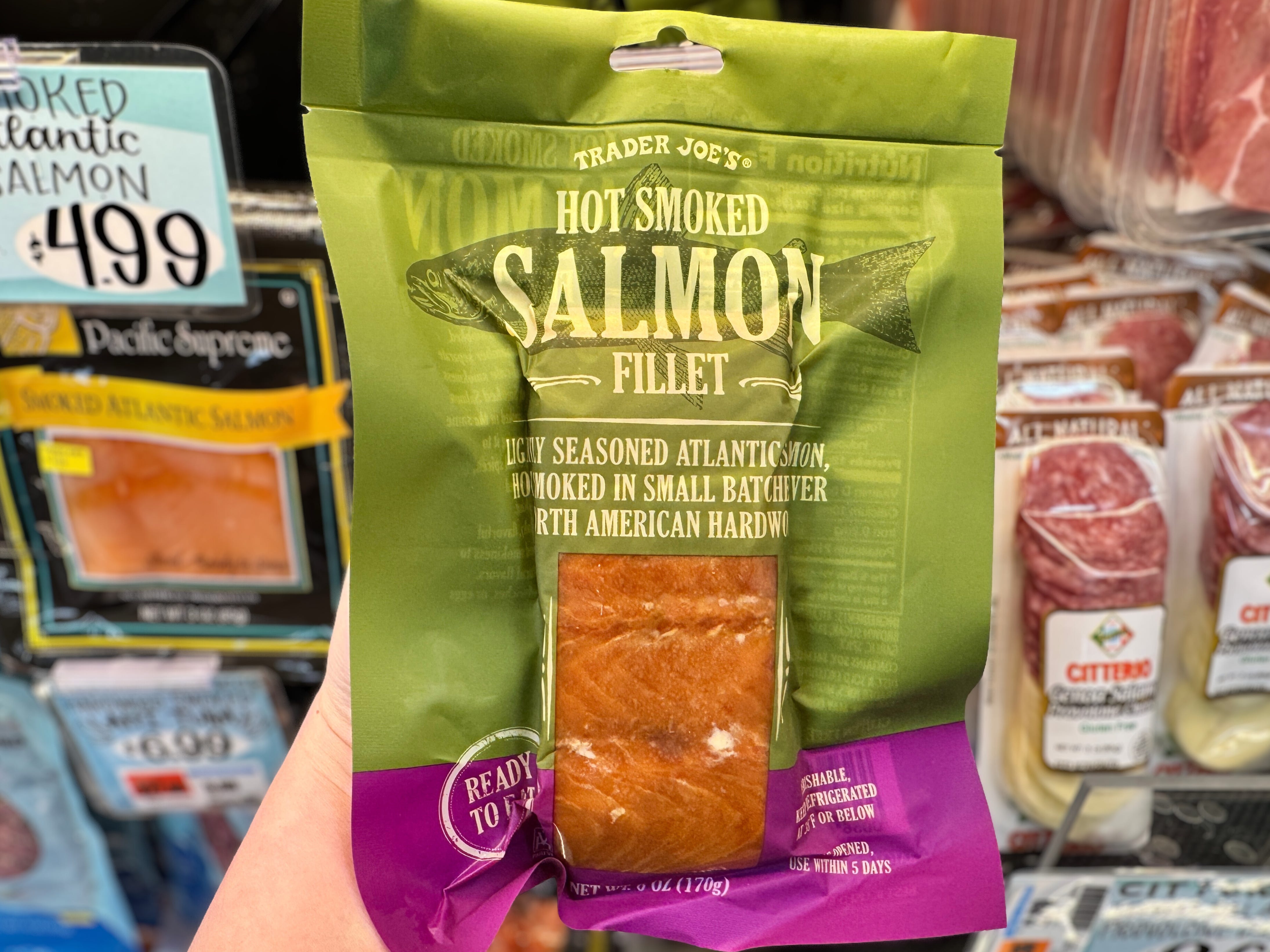 A hand holding a bag of Trader Joe's smoked salmon filet.