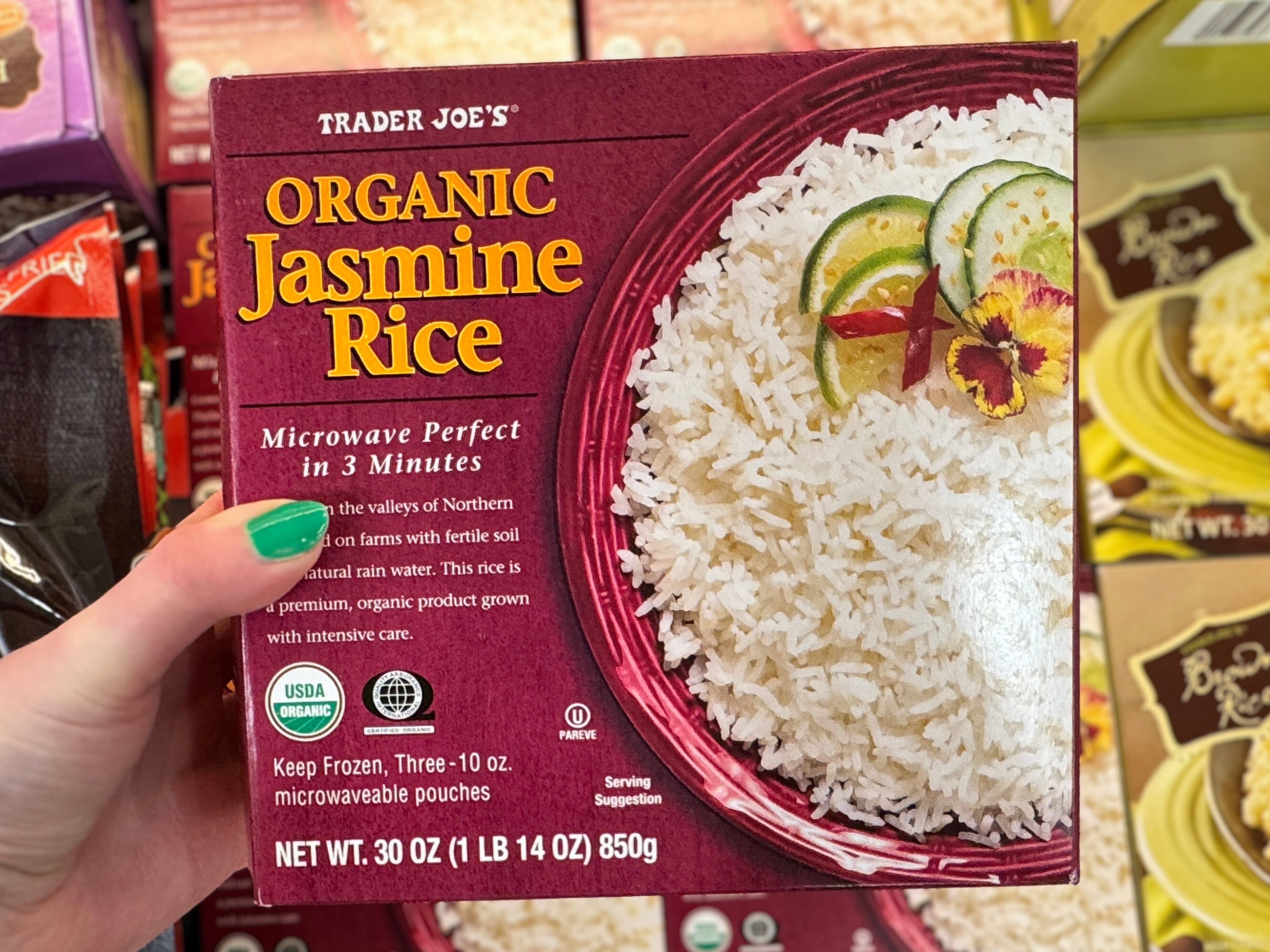 A hand holding a box of Trader Joe's jasmine rice.