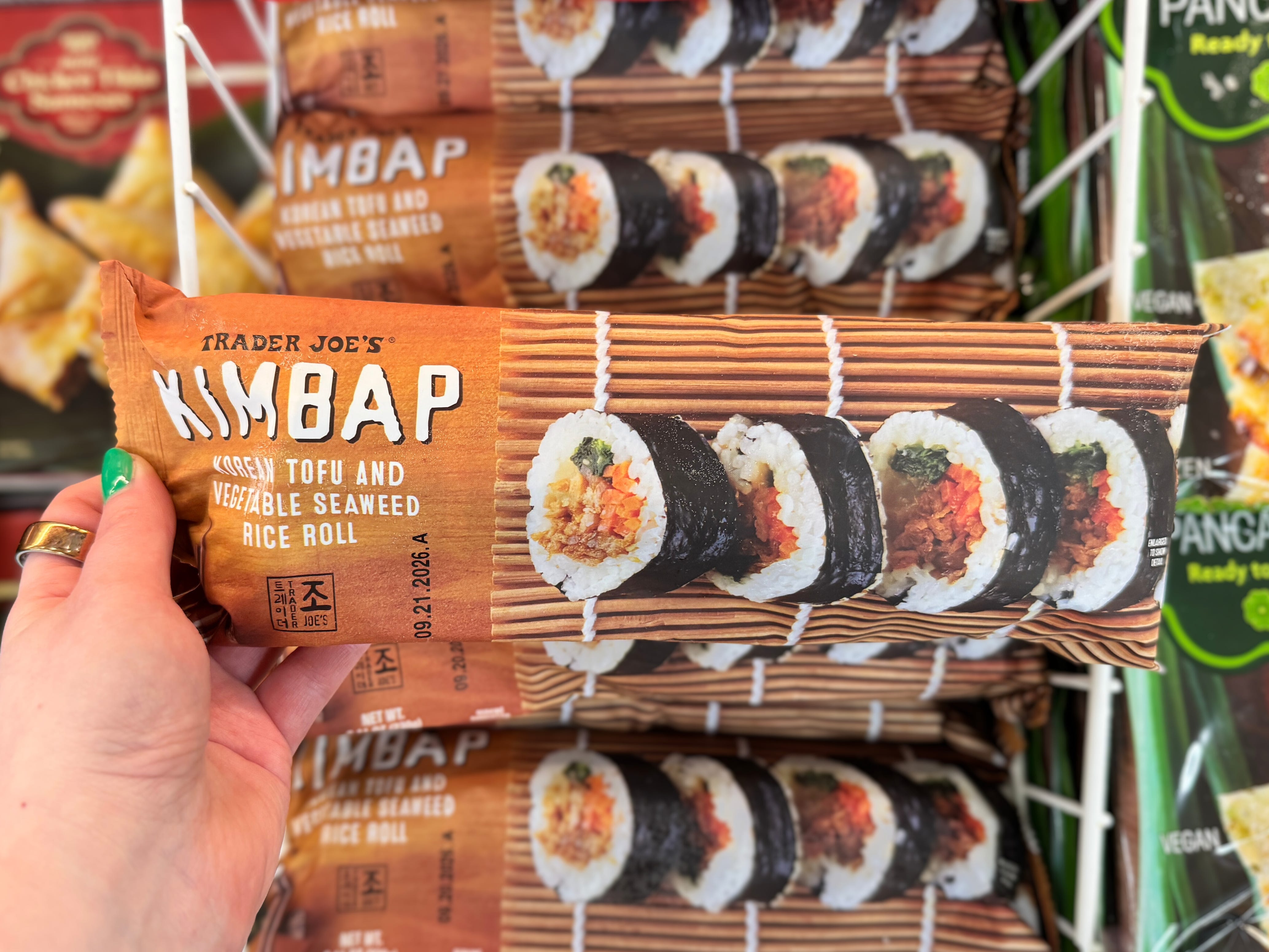 A hand holding a package of Trader Joe's Kimbap.