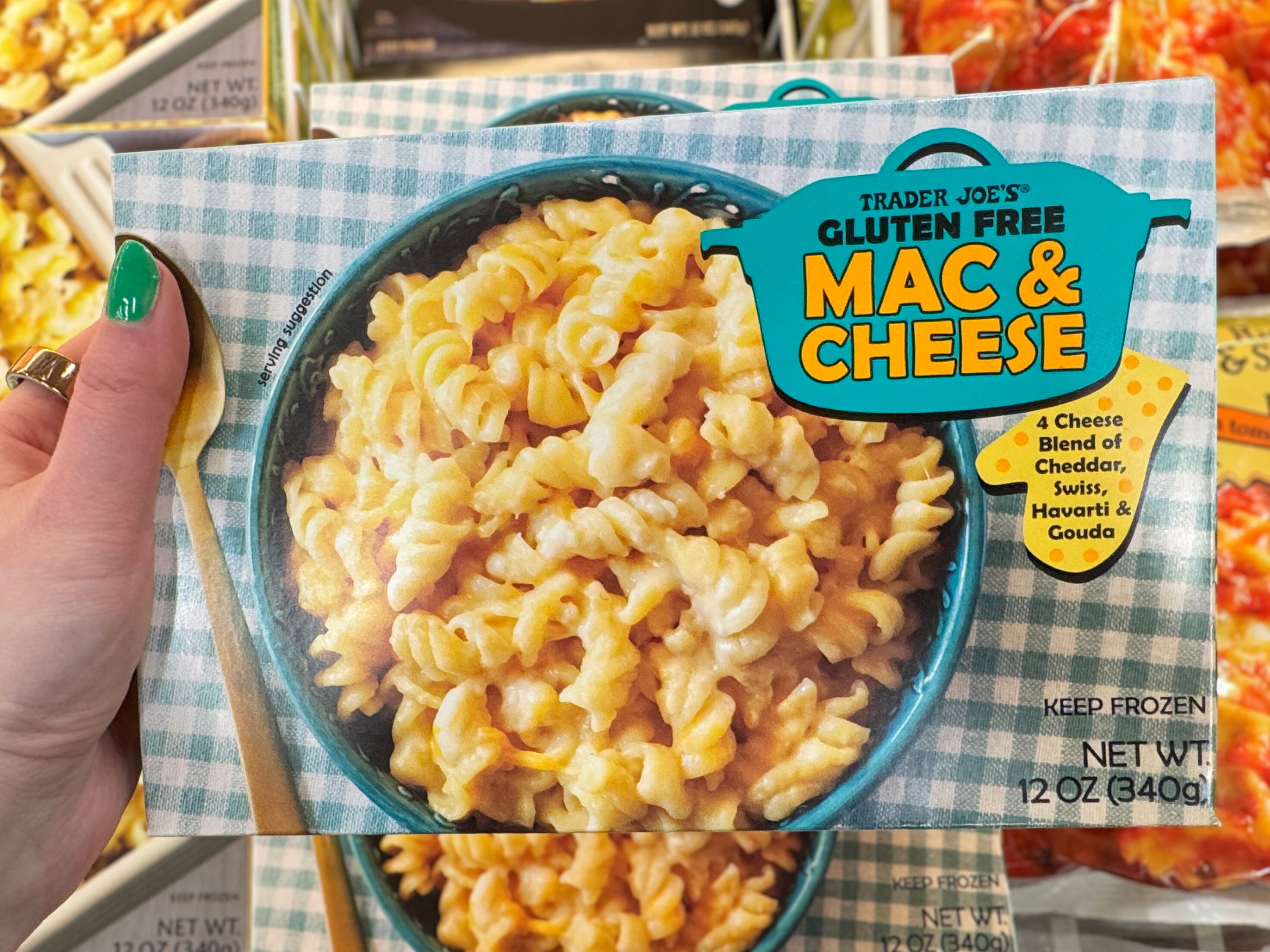 A hand holding a box of Trader Joe's gluten-free mac and cheese.