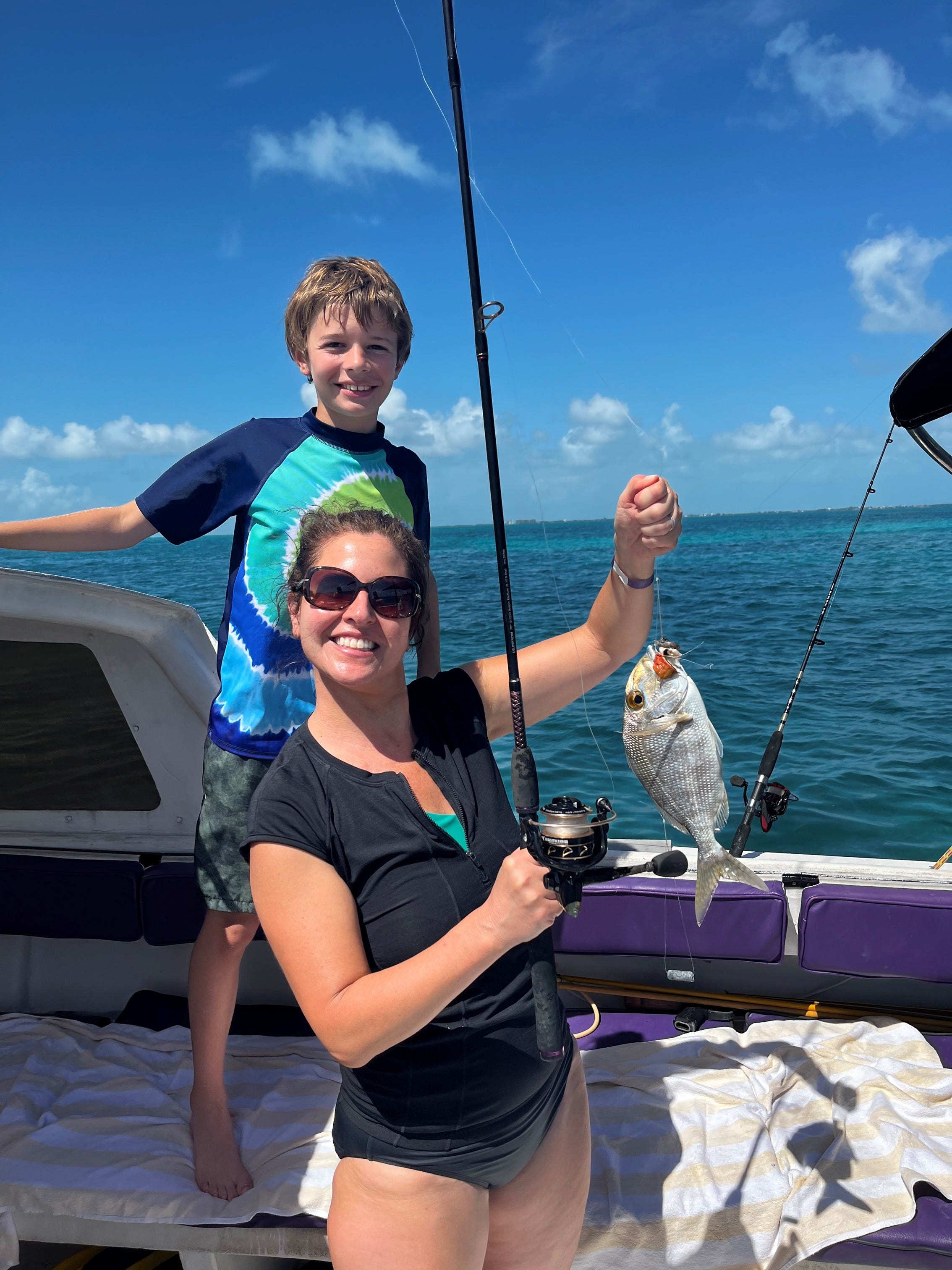 Author Christina Valhouli holding fish with boy behind her on boat