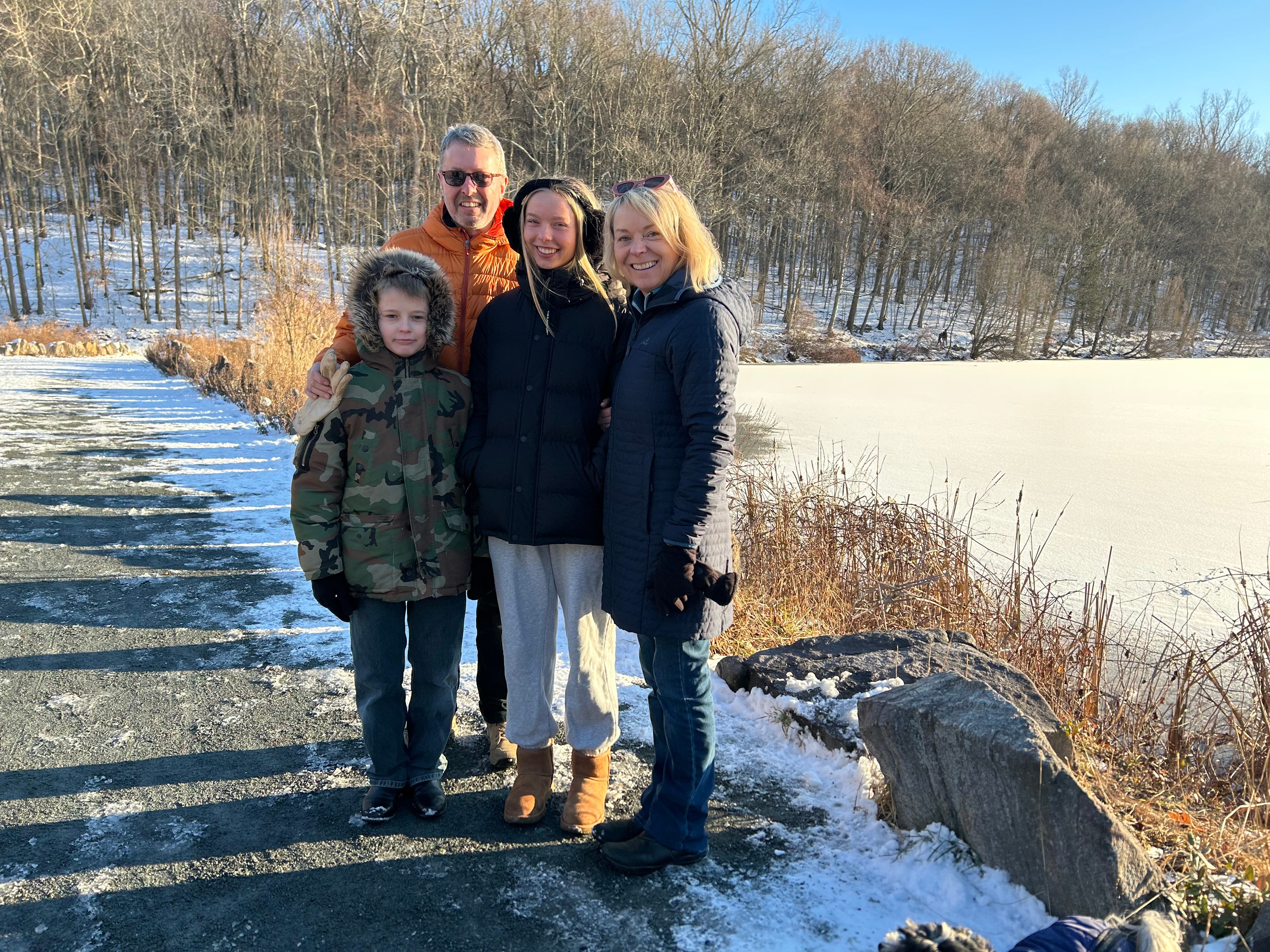 A family of four standing beside a frozen lake