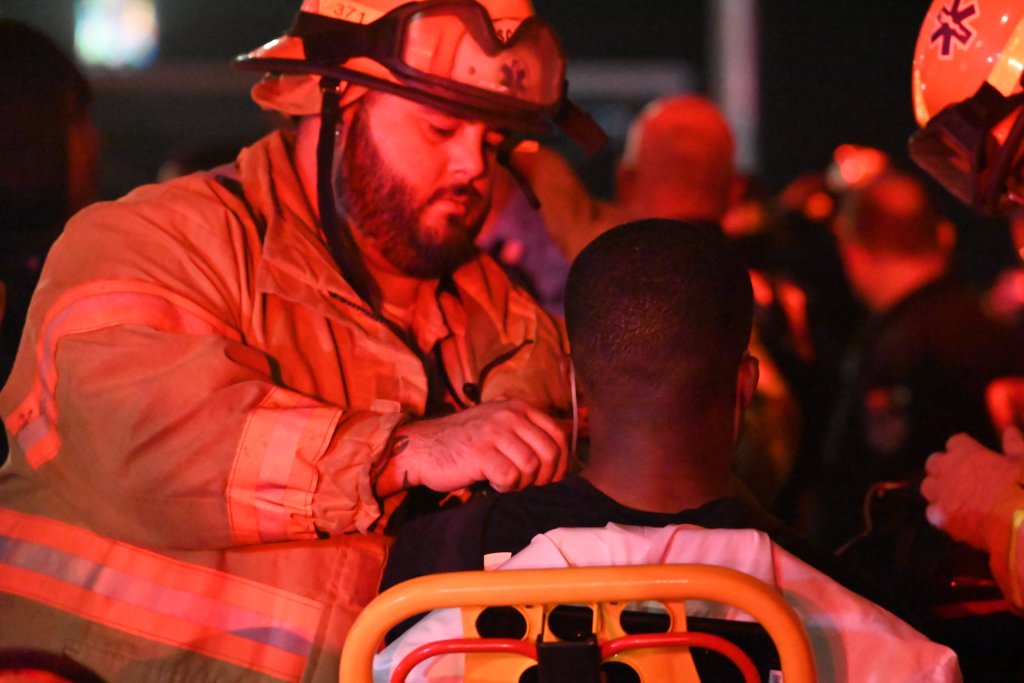 FDNY firefighter assisting a person at a three-alarm fire.