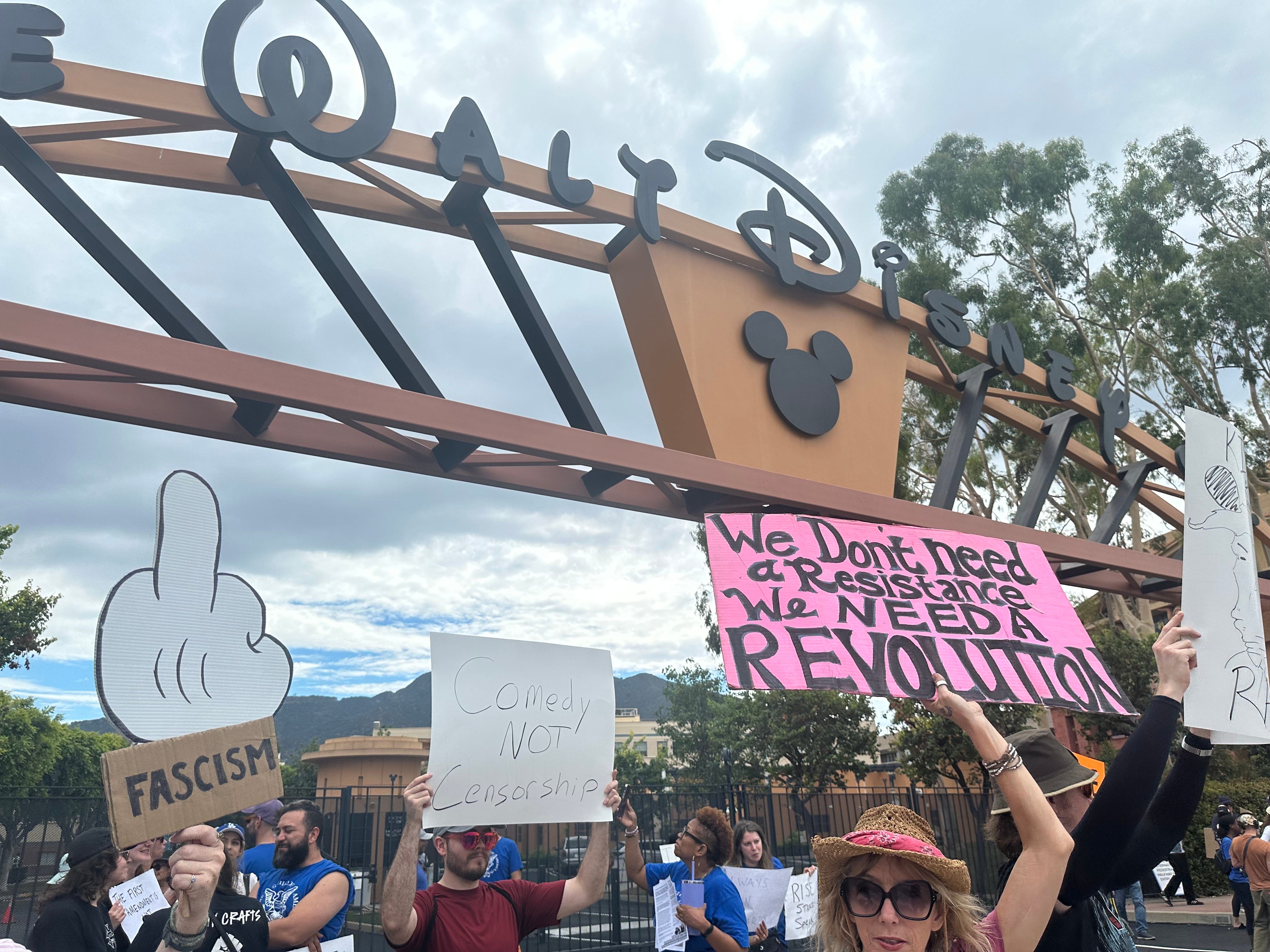 Protester holding sign in front of Disney that reads, 