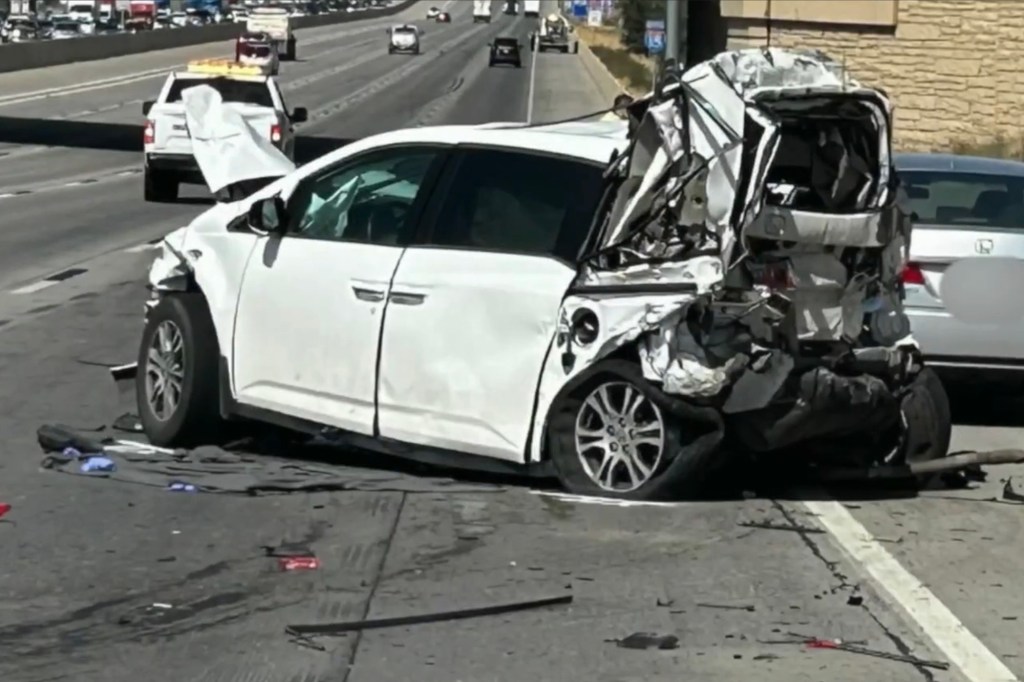Severely damaged white minivan in a highway accident.