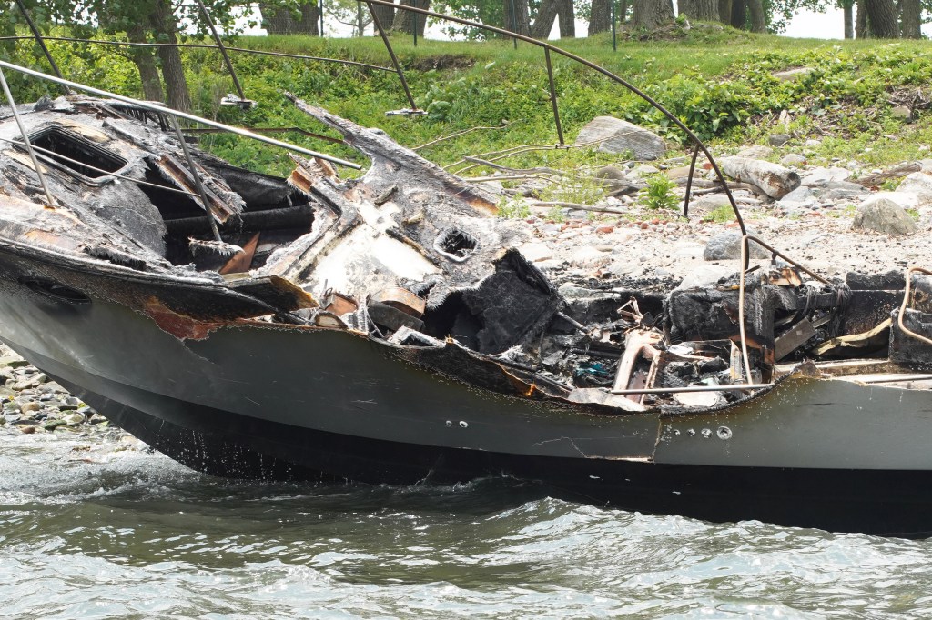 Burned-out boat in the water.