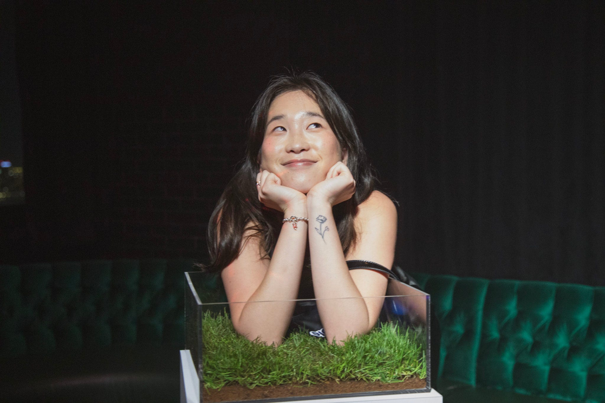 A young woman rests her chin in her hands while posing with a box of turf.