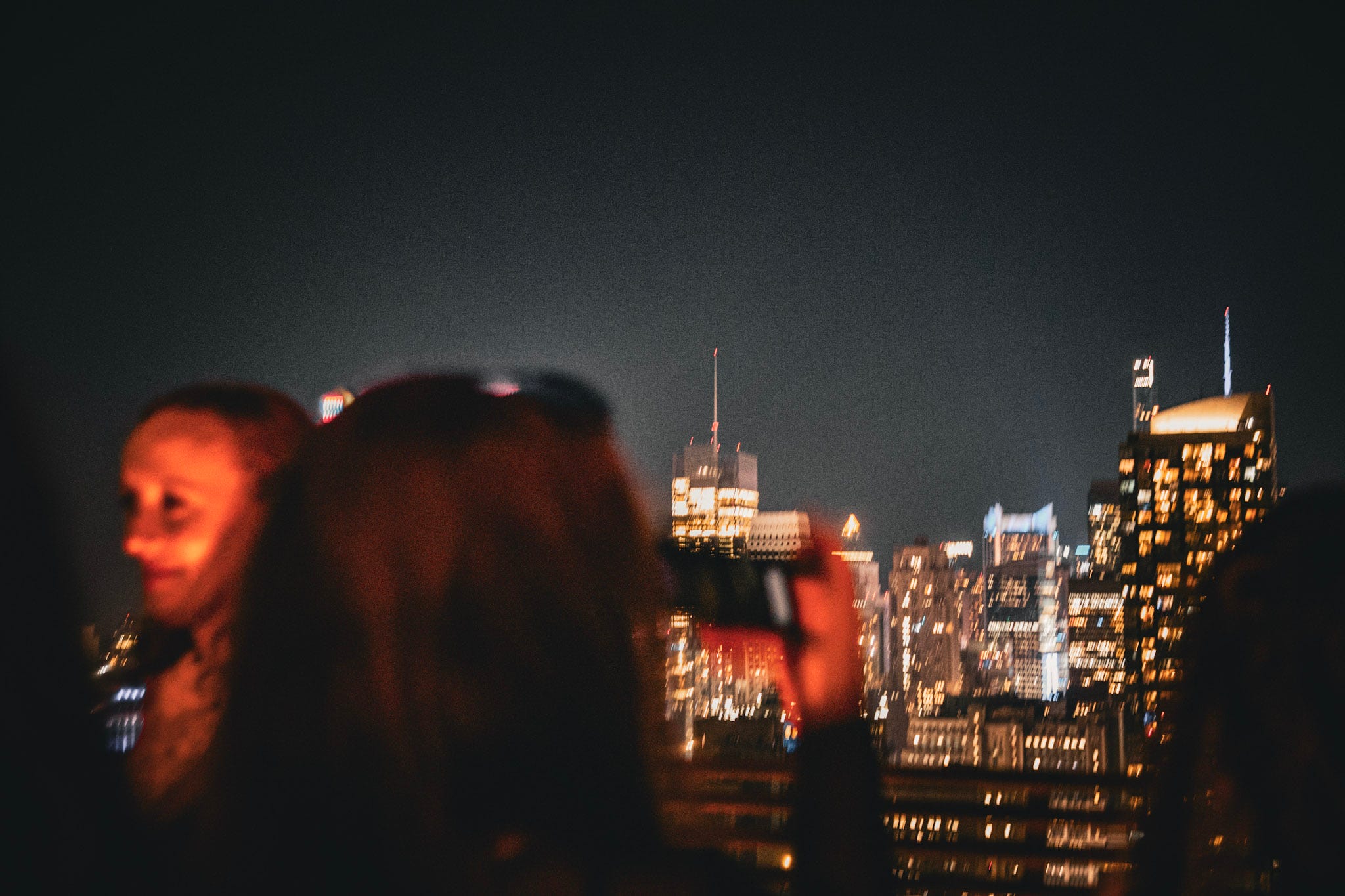 A woman snaps a phoot of the skyline on a rooftop.
