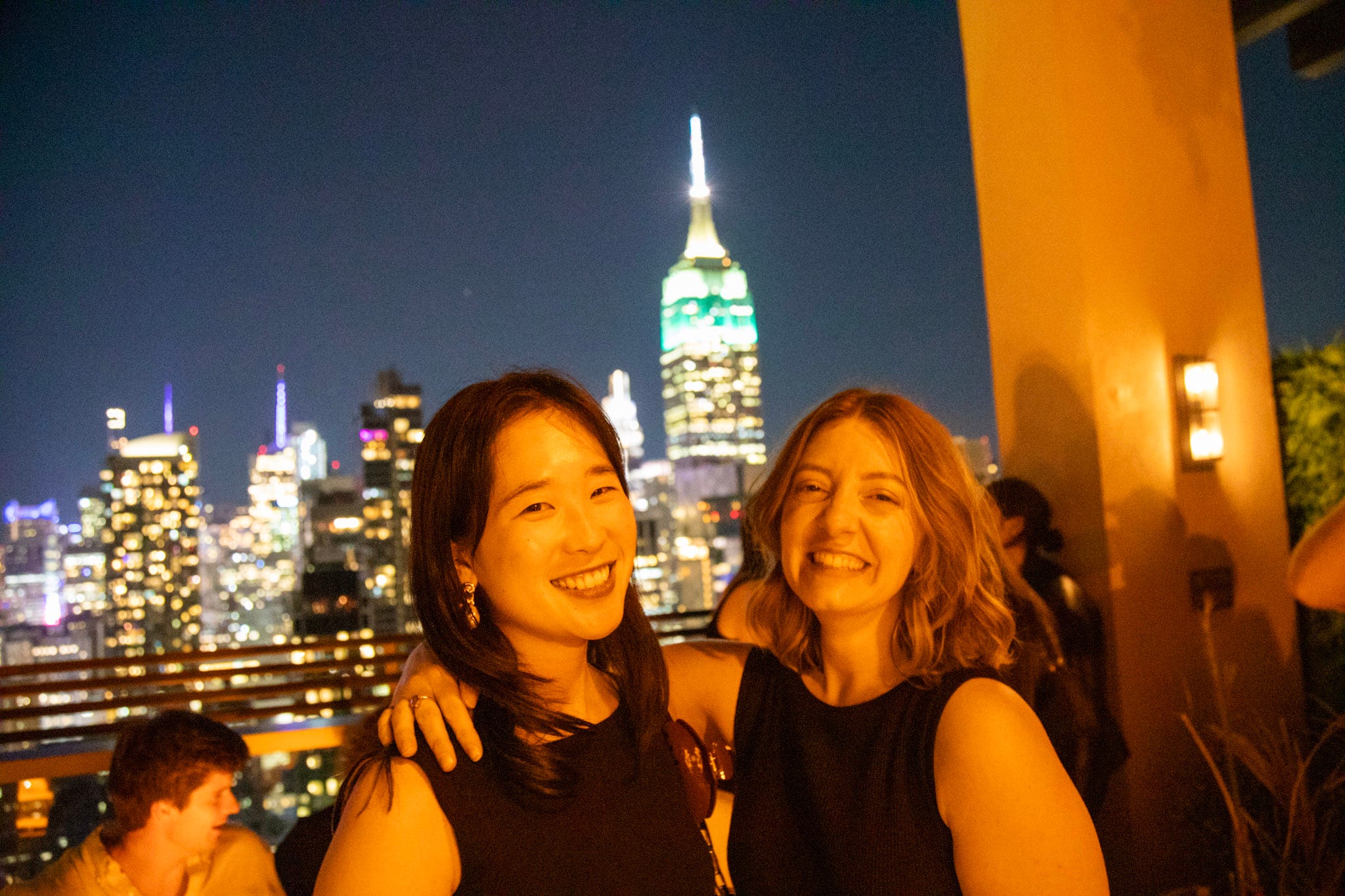 Twom women smile on a Manhattan rooftop.