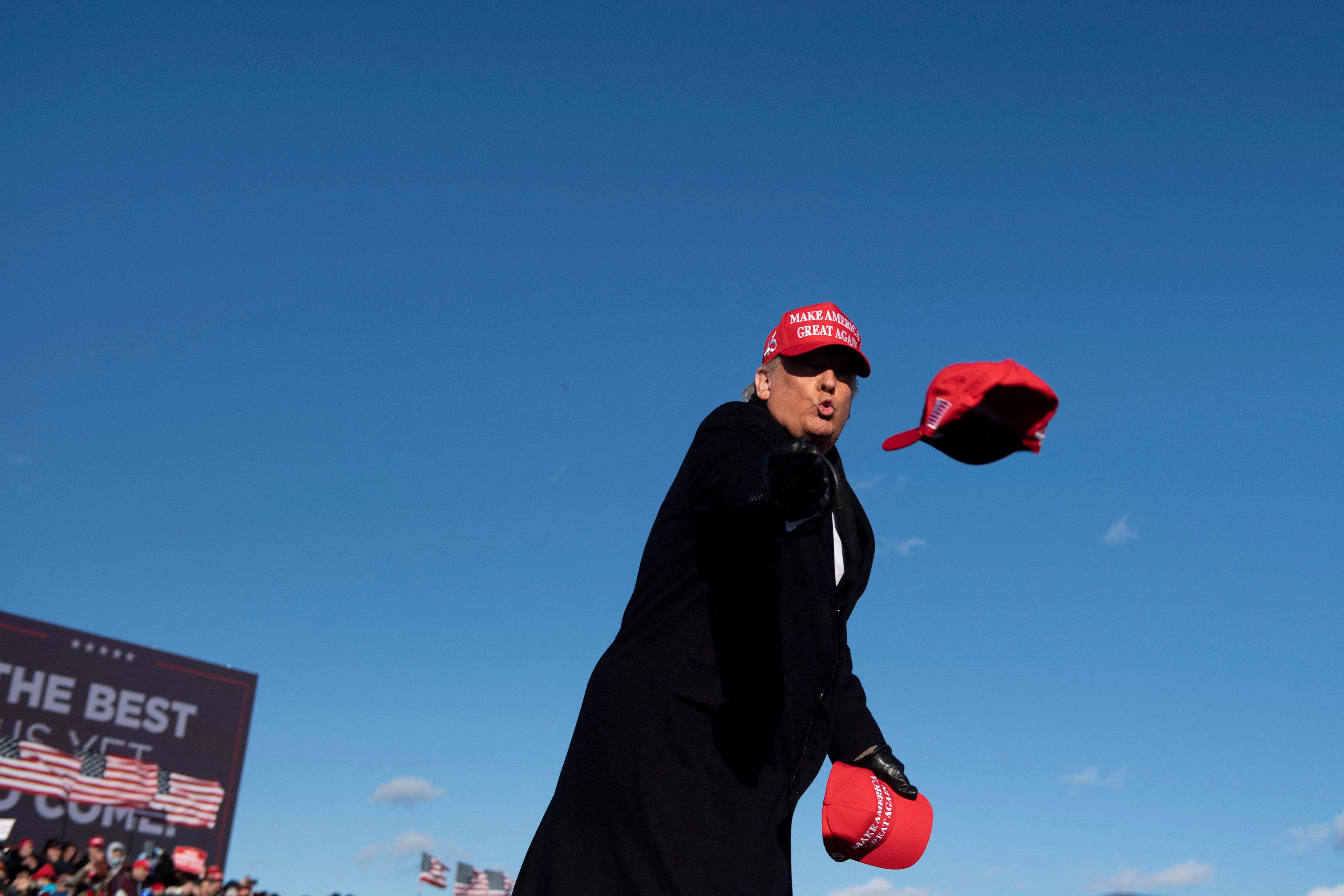 President Donald Trump throws hats to supporters during a Make America Great Again rally in 2020.