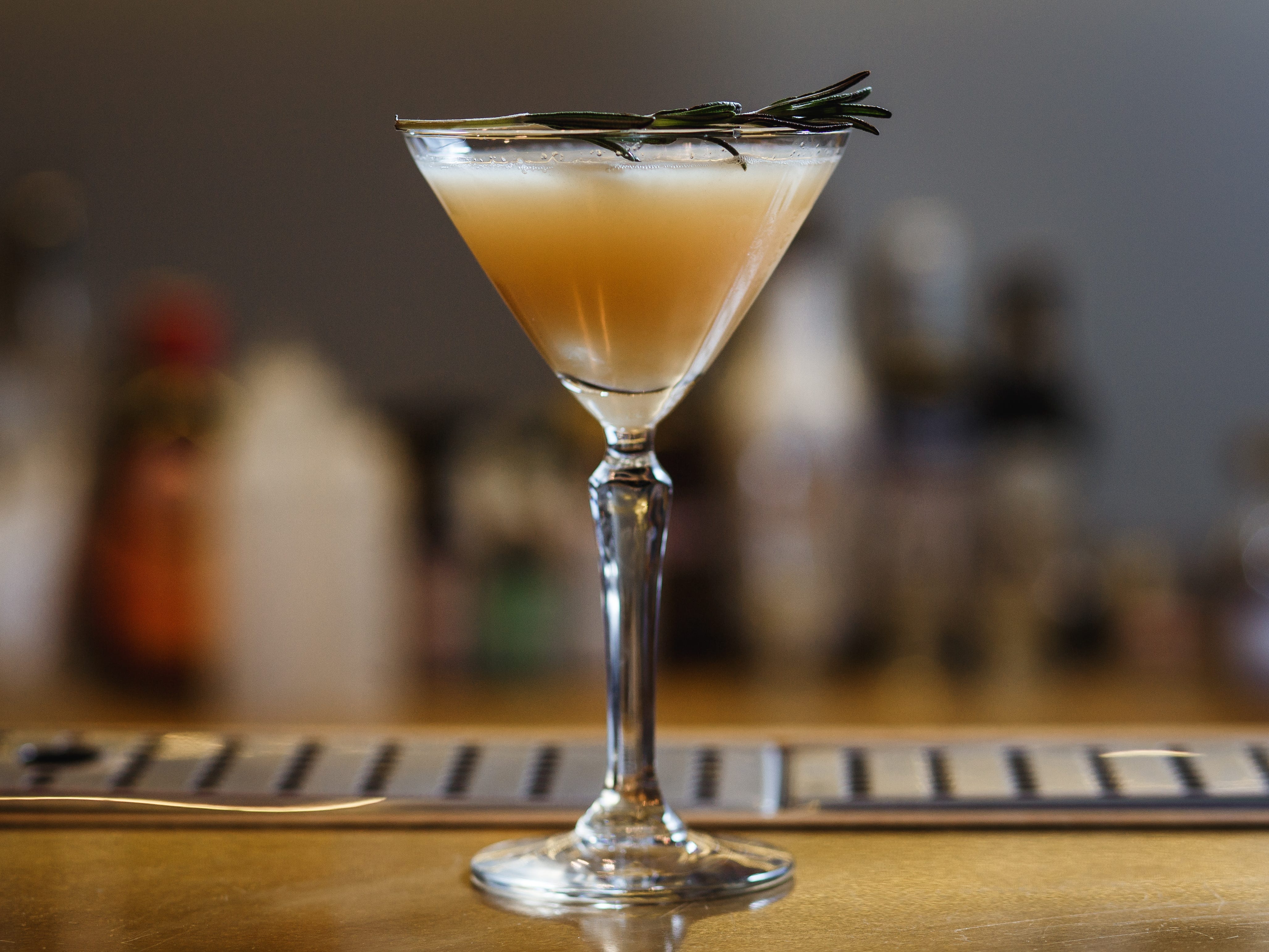 A martini that's topped with a sprig of rosemary.
