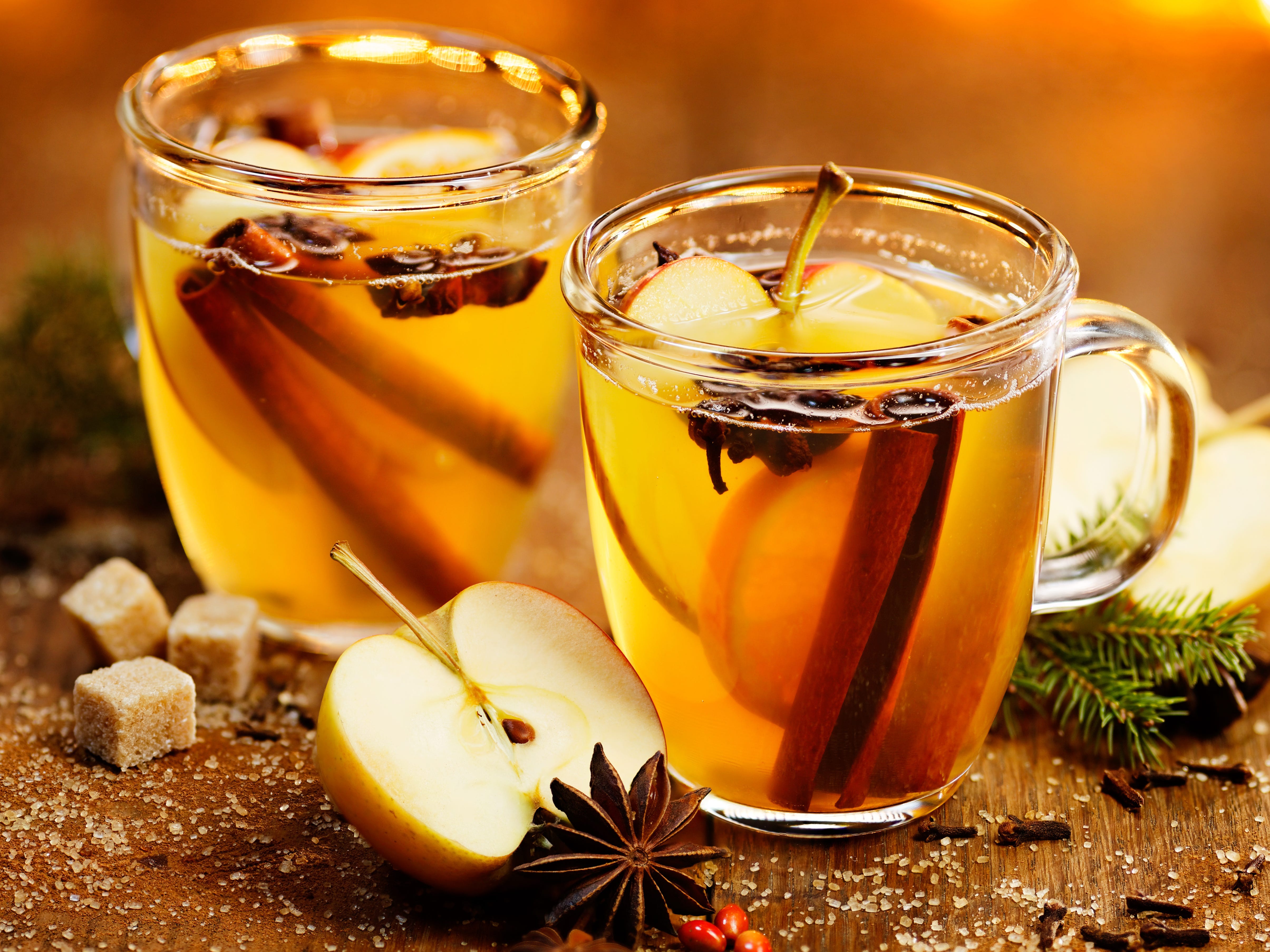Two hot toddies with apple slices and cinnamon inside.