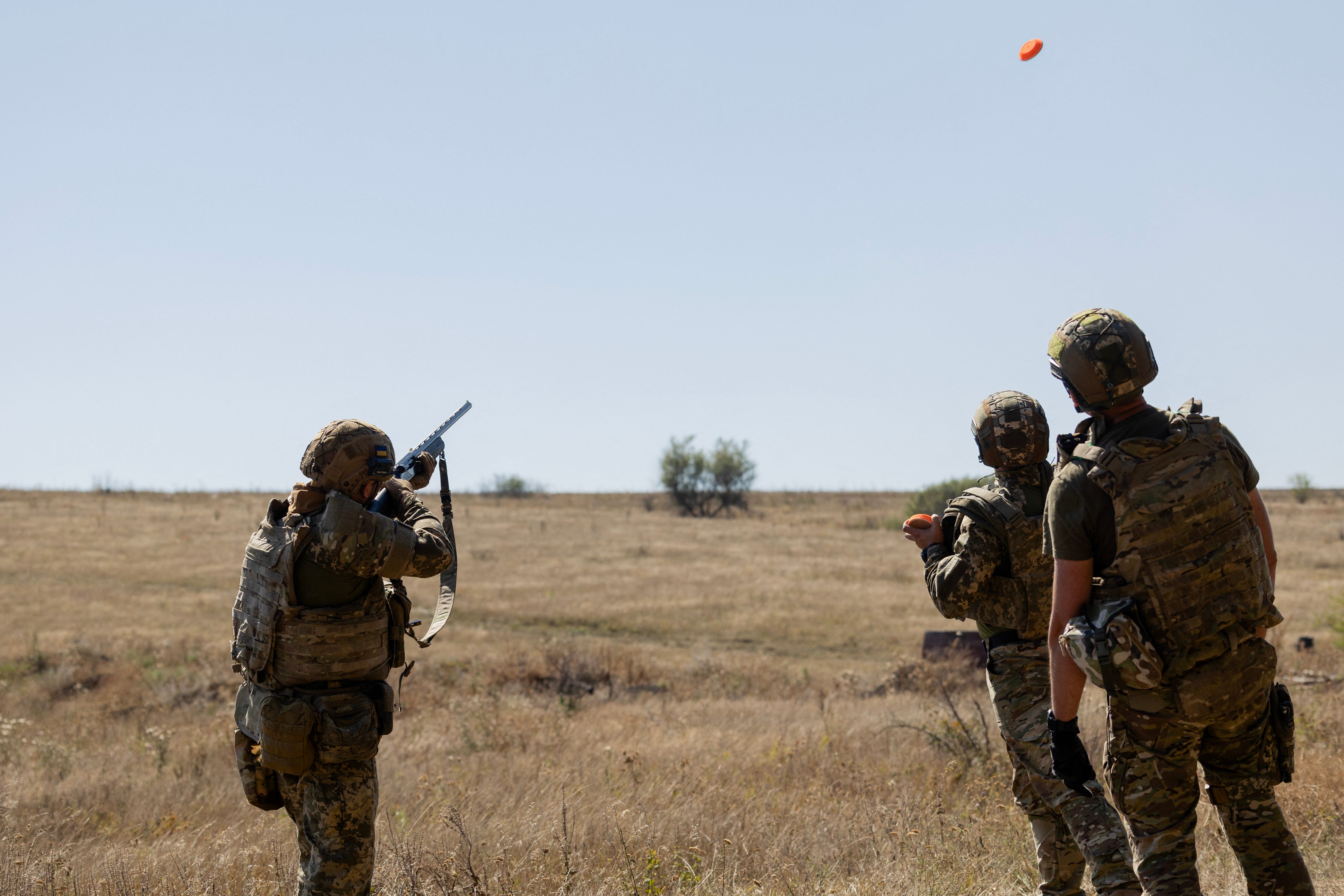 Ukrainian troops practice using shotguns in a field.