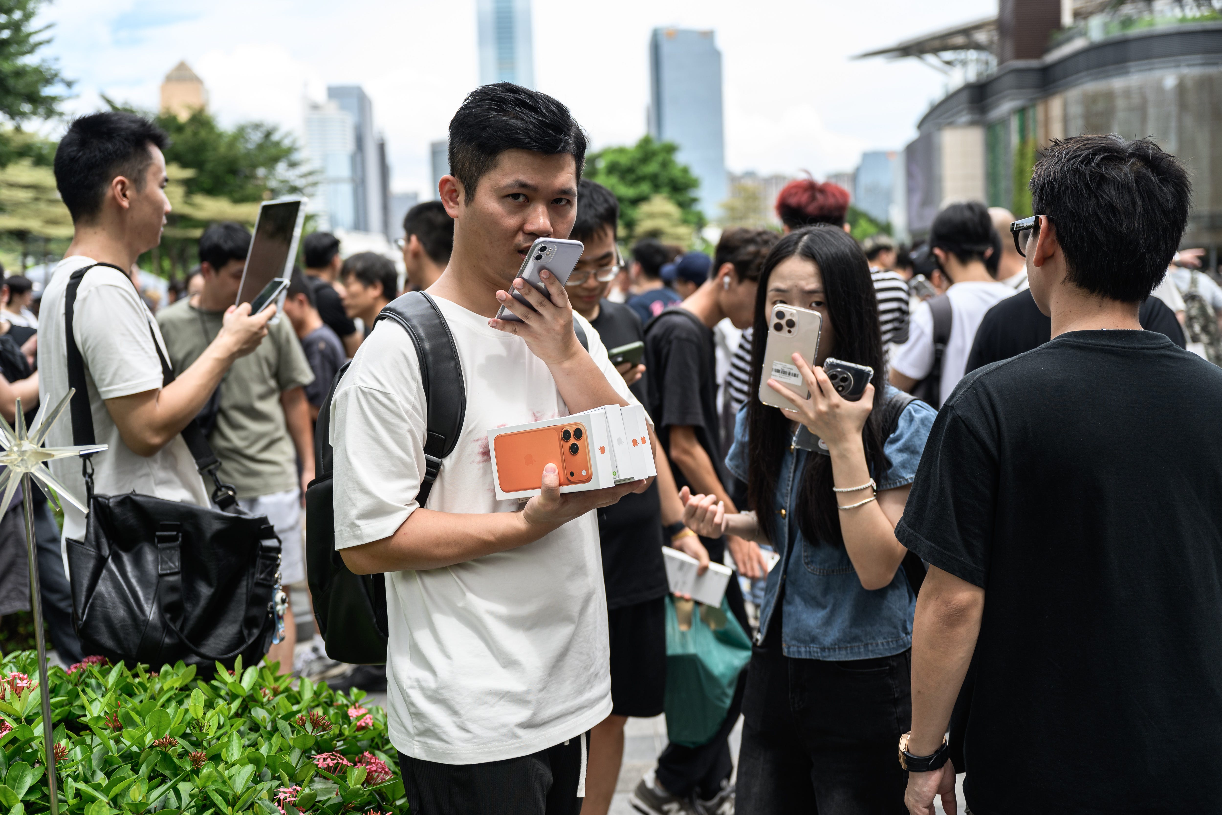 Person in Chian speaking on the phone while holding iPhone 17 Pro boxes