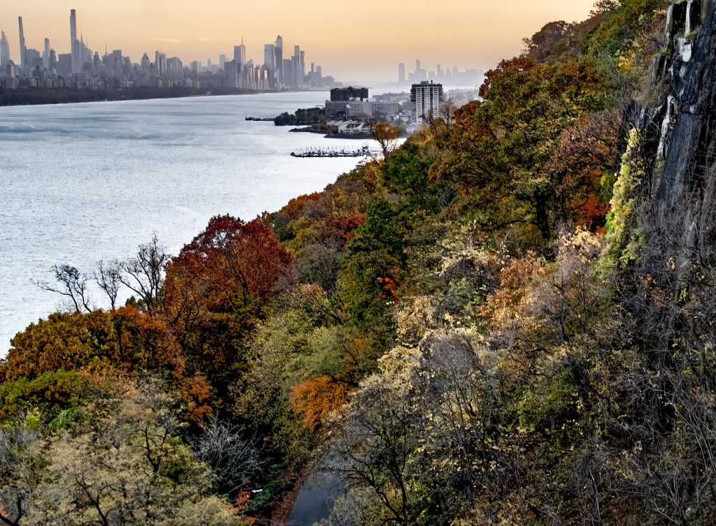 Autumn foliage along the Hudson River, with the New York City skyline in the distance.