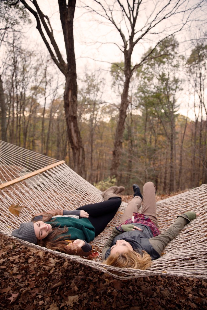 Two young women relaxing in a hammock in a forest.