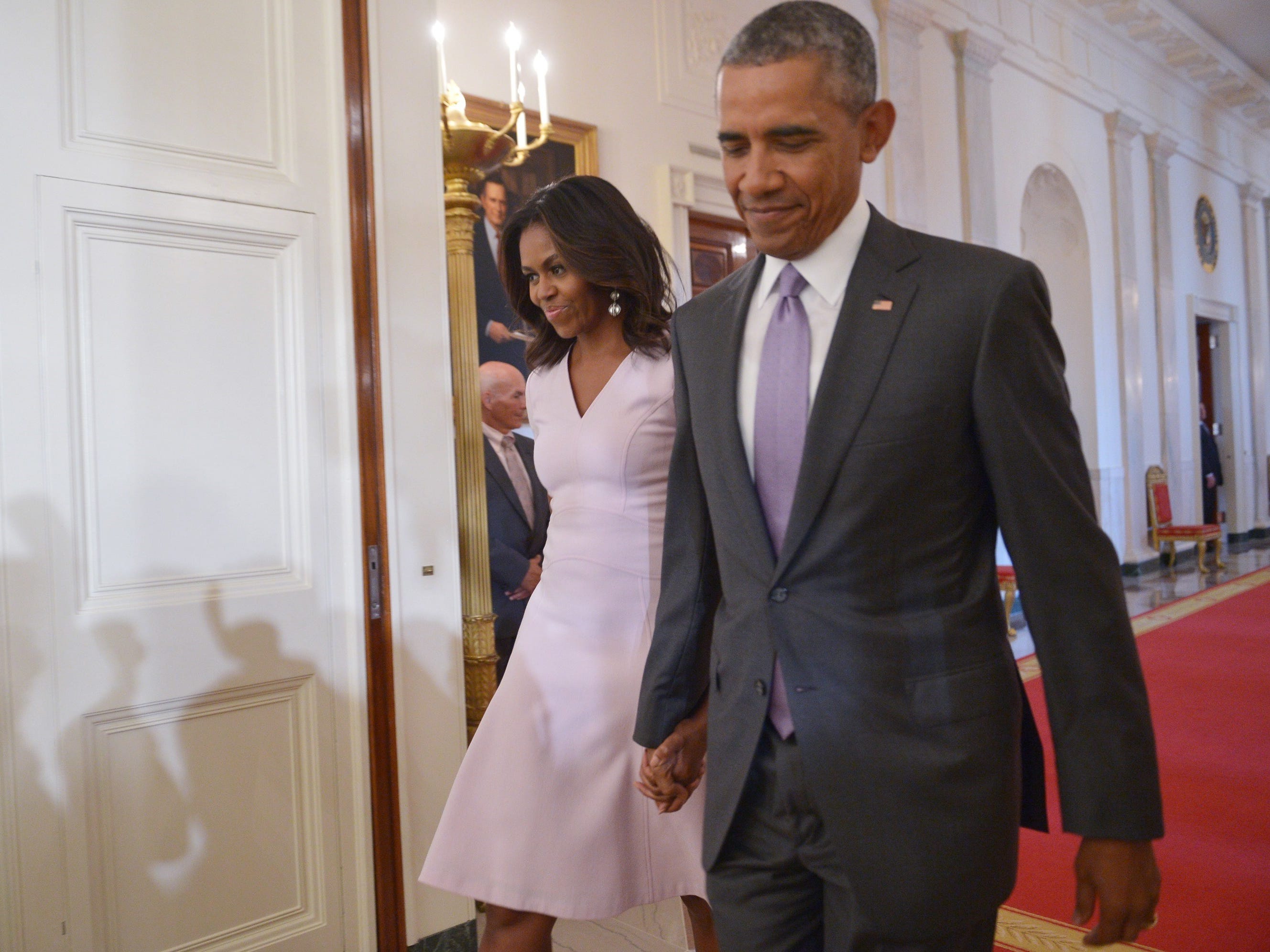 Barack and Michelle Obama walk together in the White House.