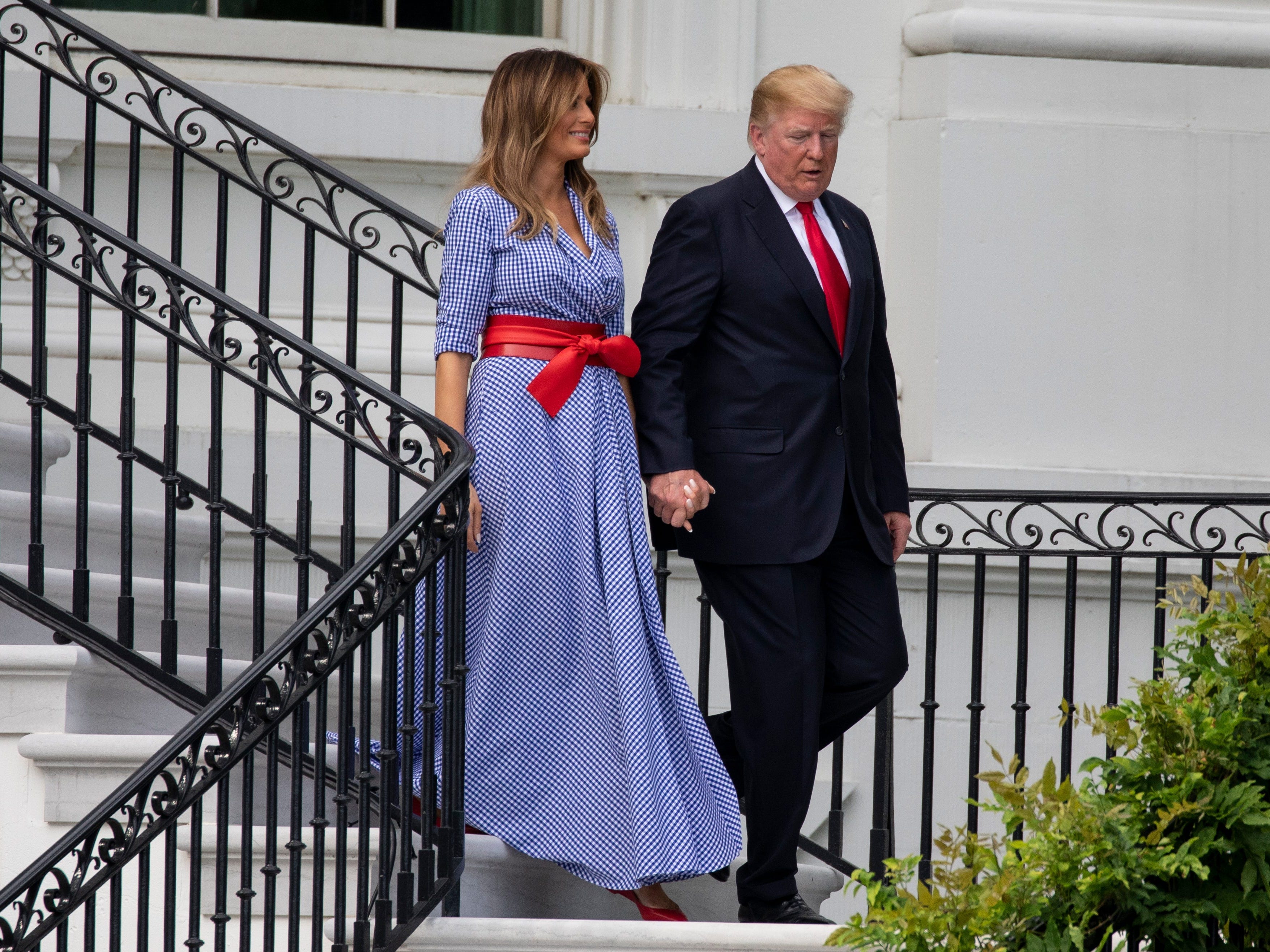 Donald and Melania Trump walk down the White House steps.
