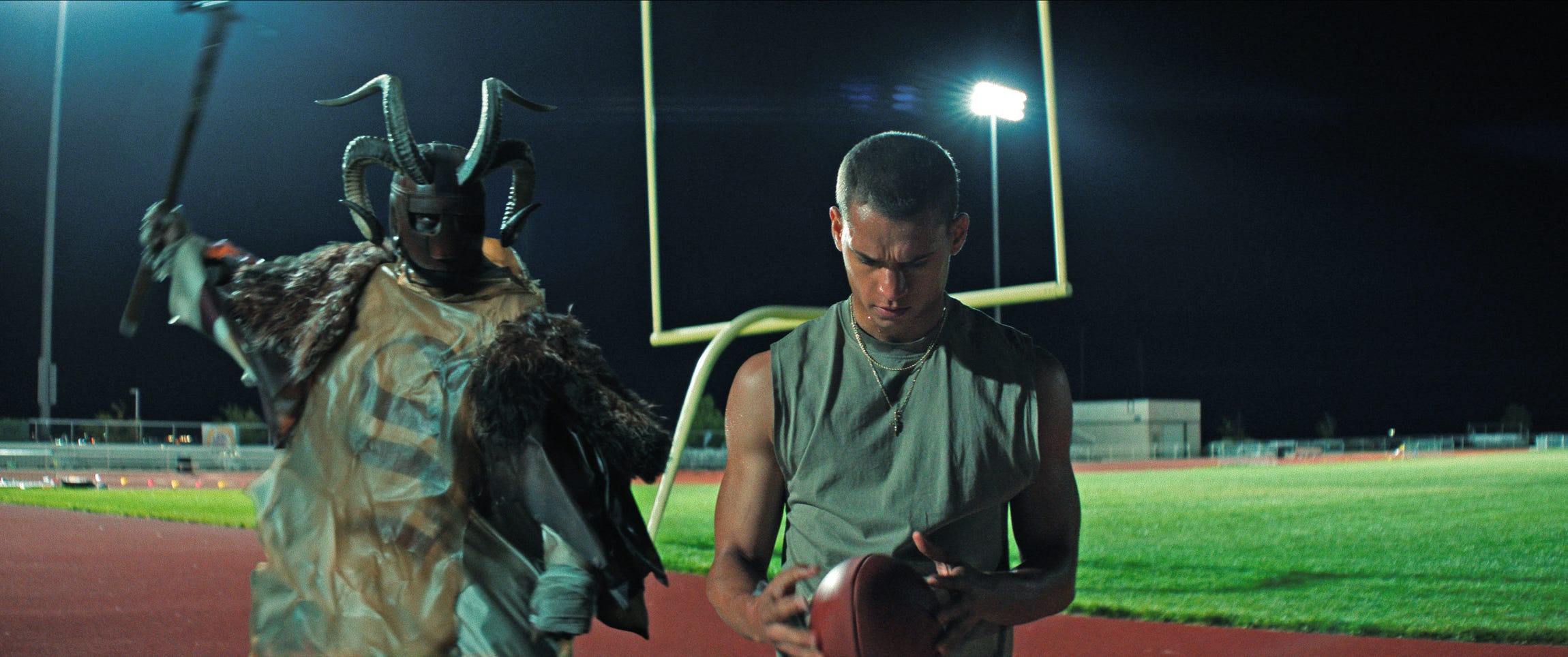 Tyriq Withers holding a football next to someone with a hammer