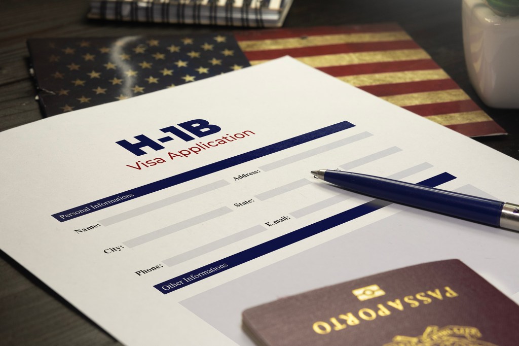 H-1B visa application on a table with a pen and passport.