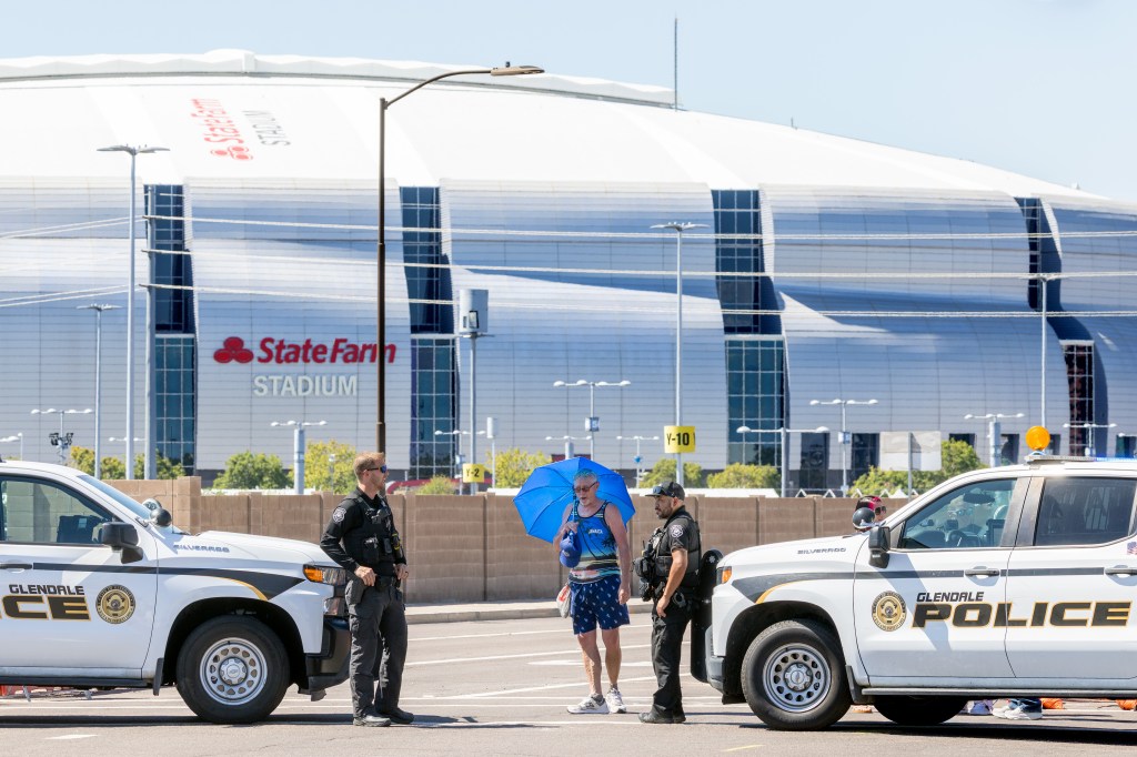 Three U.S. Customs and Border Protection officers in camouflage uniforms standing in front of State Farm Stadium.