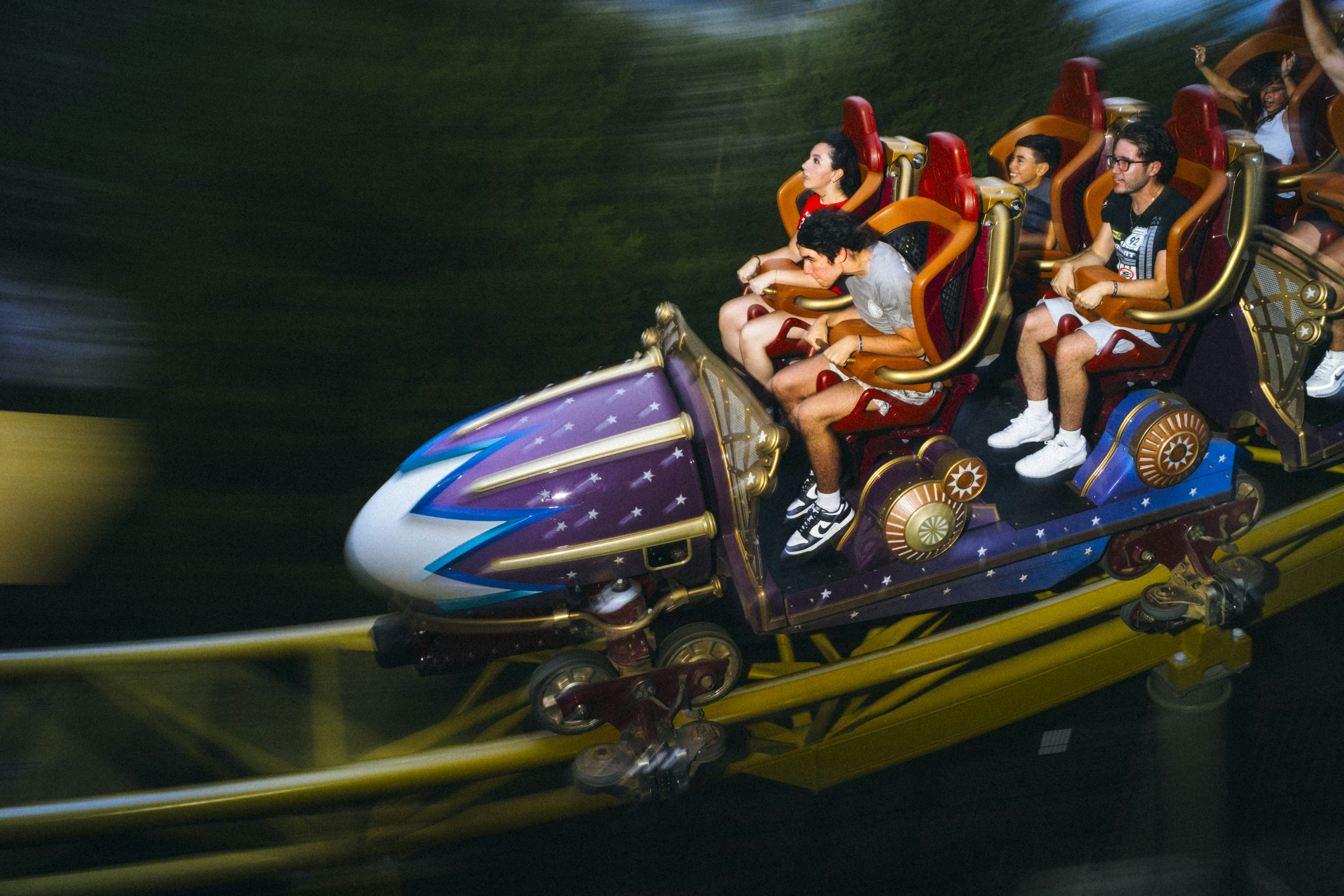 People on Stardust Racers, a purple and blue roller coaster with red chairs at Universal Epic Universe