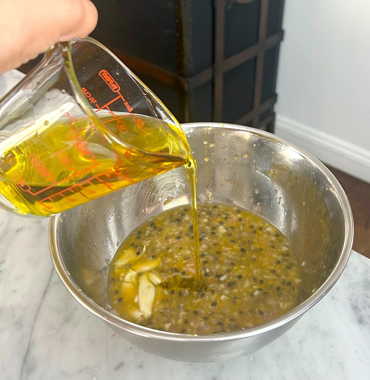 Adding olive oil to the passionfruit vinaigrette for Meghan Markle Roasted Chicken and Bread Salad
