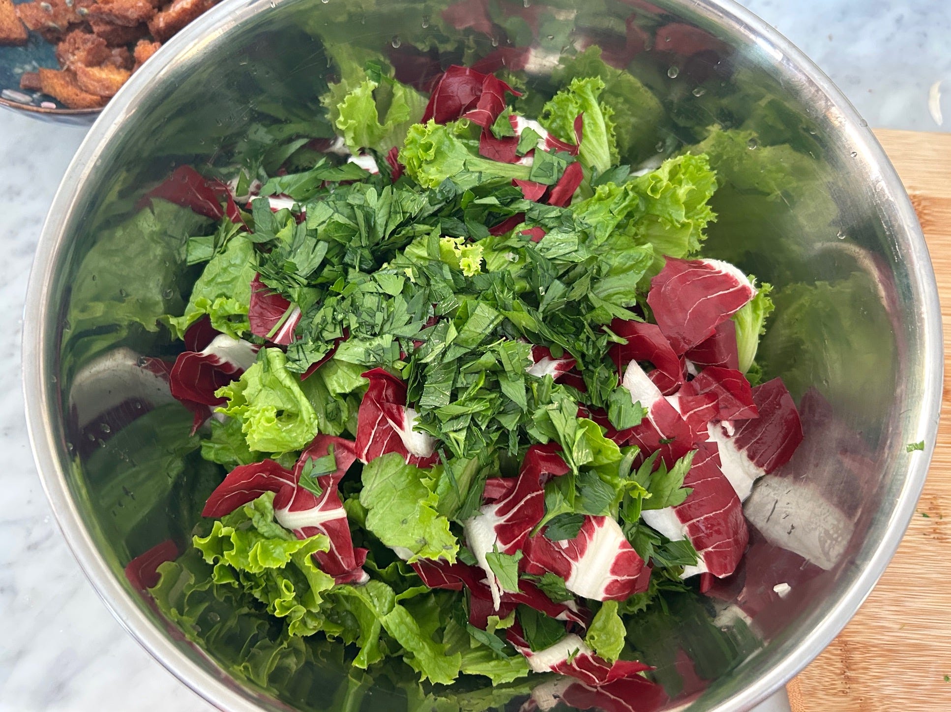 Mixing the lettuce, parsley, and radicchio for Meghan Markle Roasted Chicken and Bread Salad