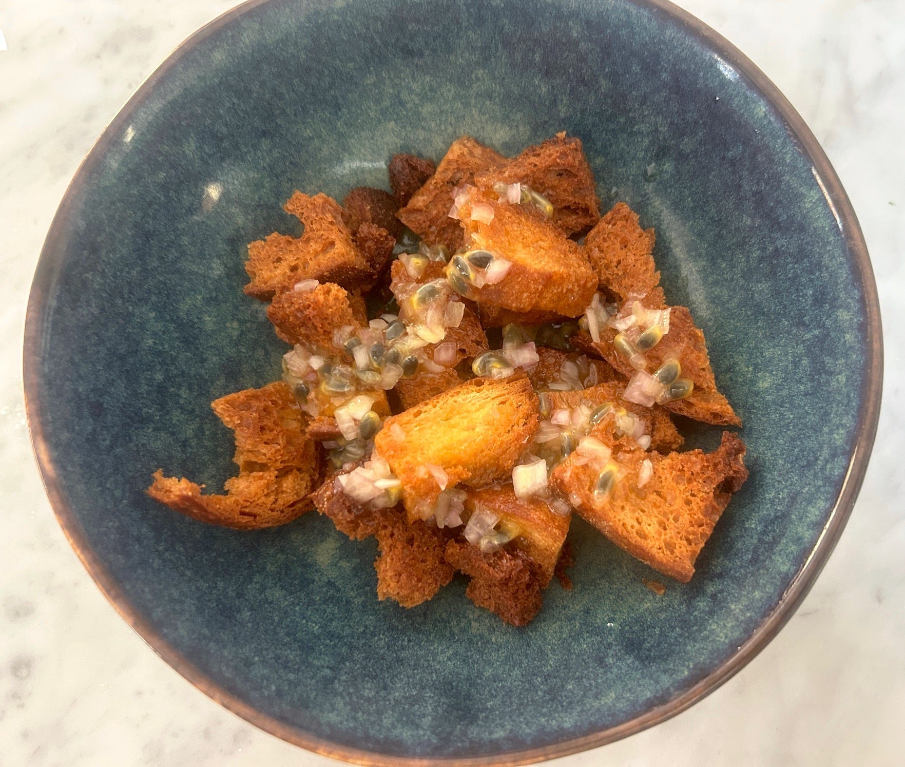Adding passionfruit vinaigrette to croutons for Meghan Markle Roasted Chicken and Bread Salad