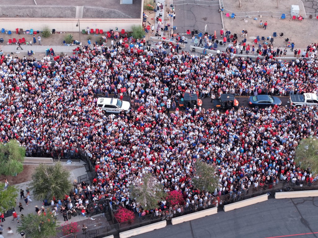 Aerial view of a large crowd wearing red, white, and blue clothing at a memorial service.