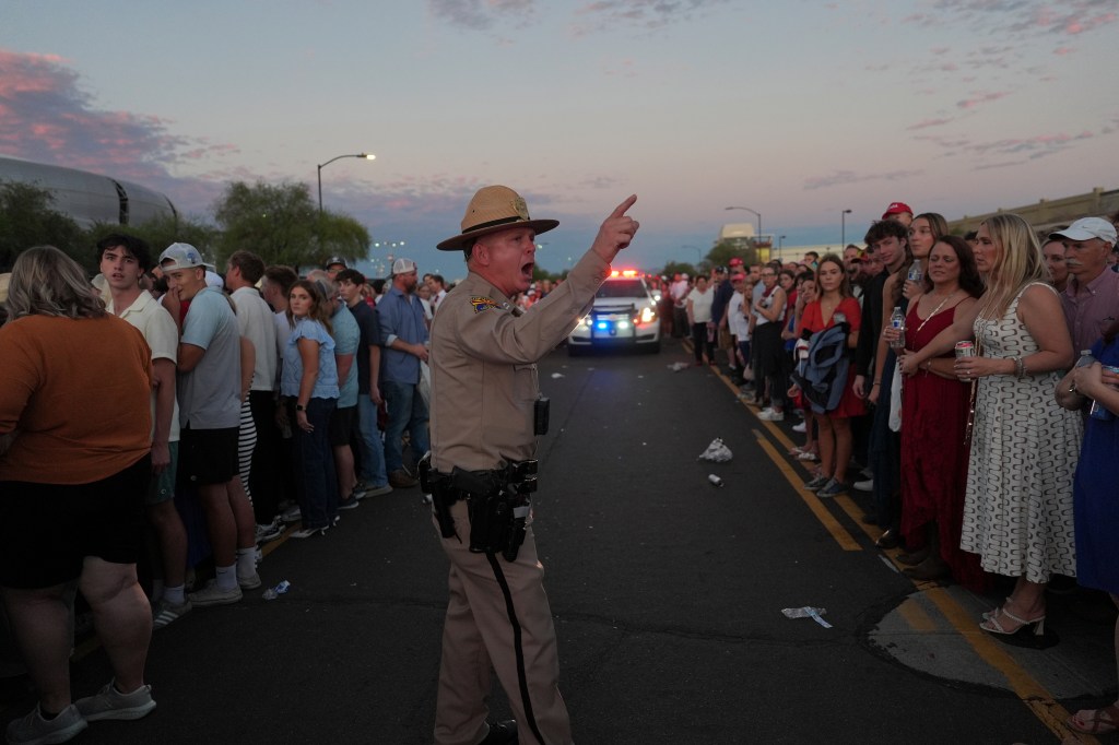 Police officer directs a large crowd gathered for a Charlie Kirk memorial.