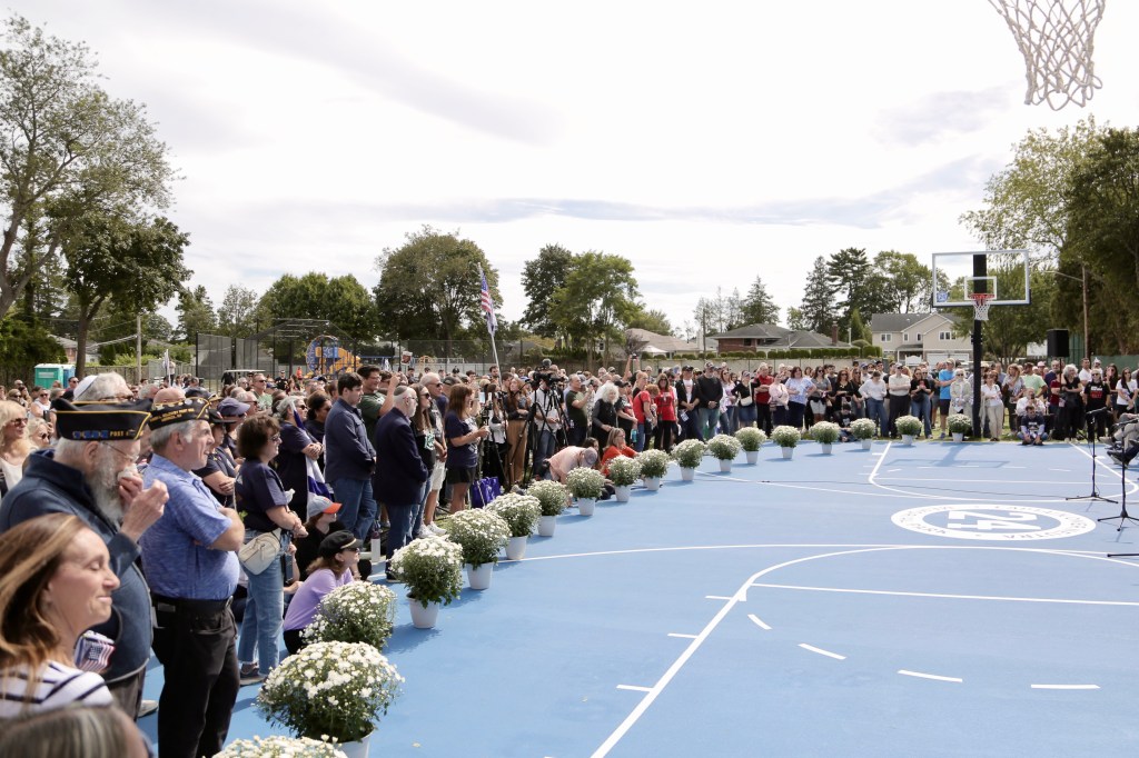 People gathered on a basketball court for the naming of the Captain Omer Neutra Memorial Park.