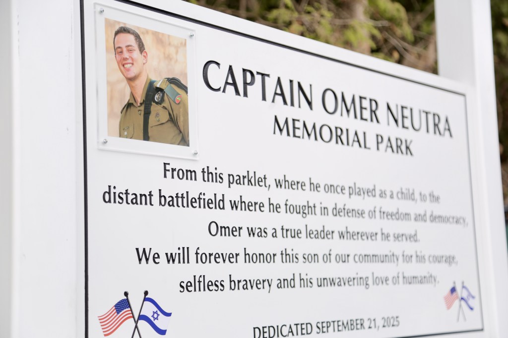 A memorial sign with a photo of Captain Omer Neutra, honoring his bravery and dedication to freedom.