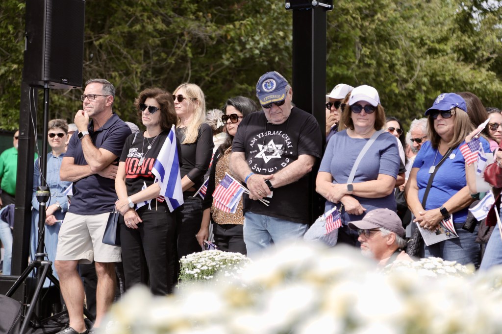 People attending the Captain Omer Neutra Memorial Park dedication, with some holding American and Israeli flags.