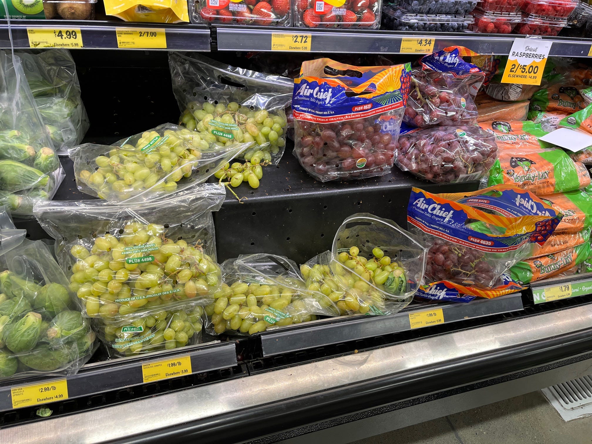 Grapes, carrots, and other fresh produce sit in a cooler case at Grocery Outlet.