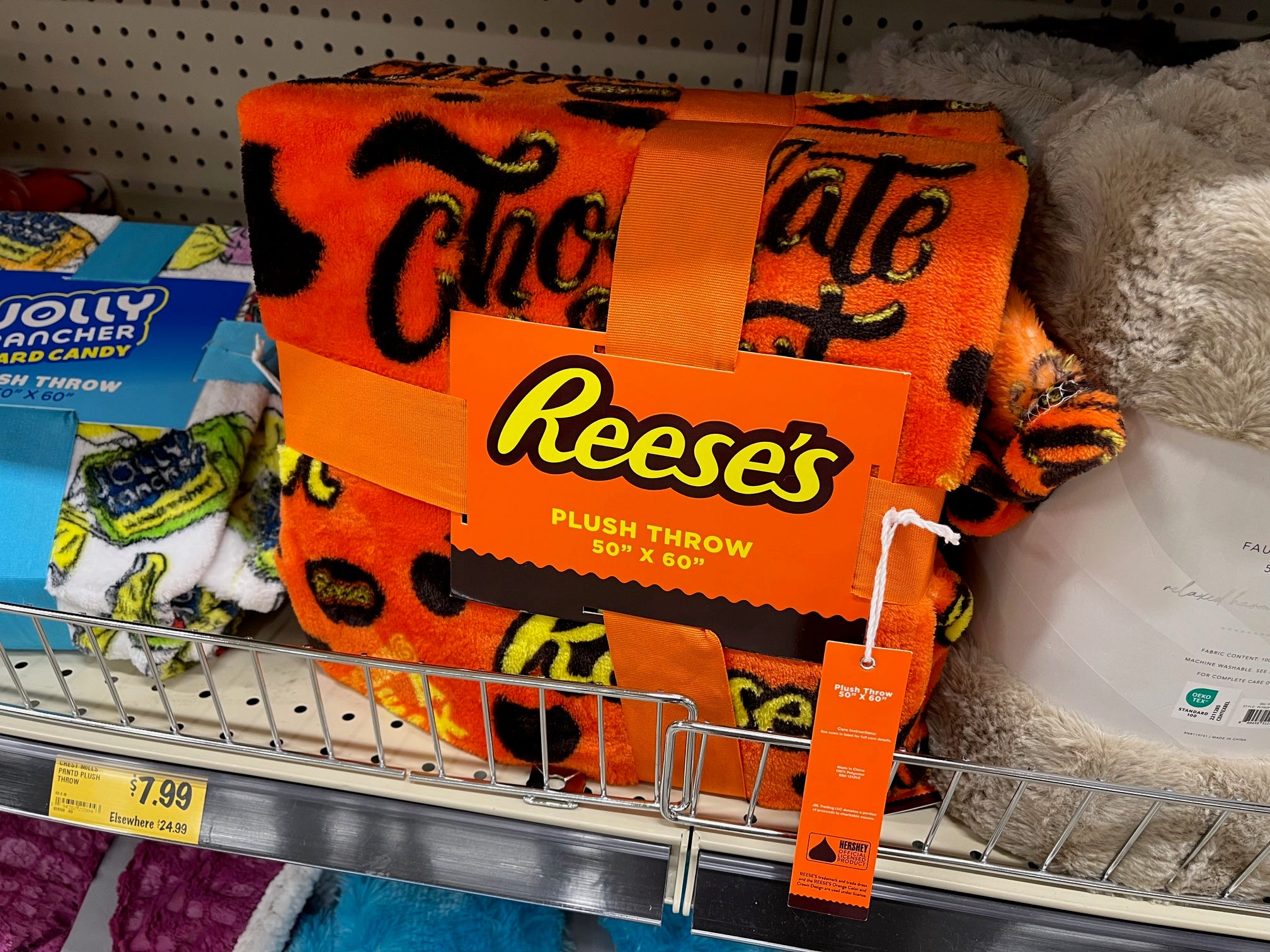 An orange Reese's-branded throw blanket sit on the shelf at Grocery Outlet.