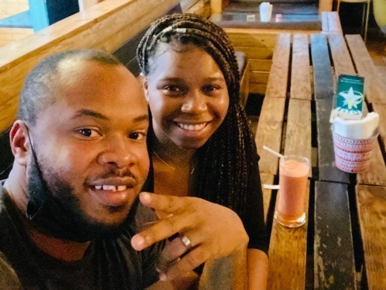 A man and a woman in a restaurant with a pink milkshake