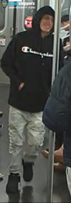 A man wearing a black Champion hoodie and light-colored pants.