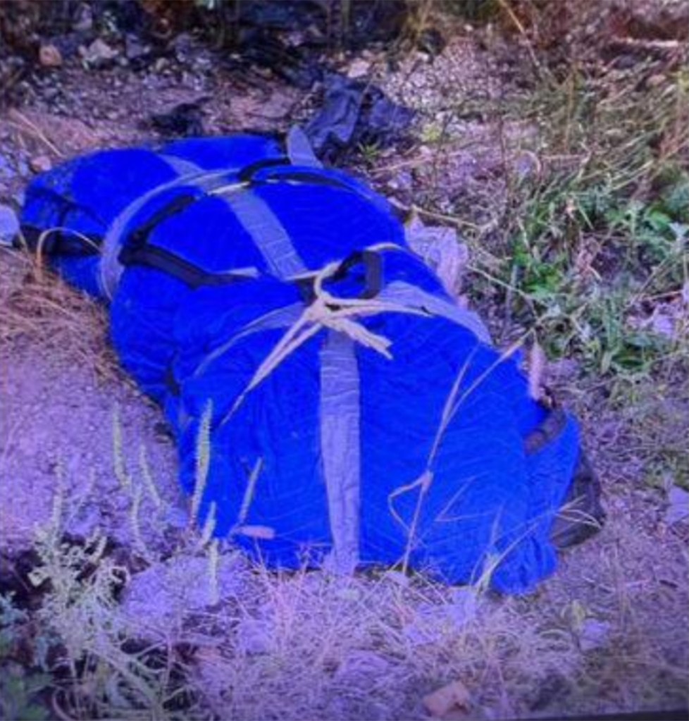 A body wrapped in a blue tarp and tied with ropes found on the ground.