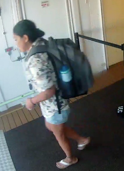 Person in floral shirt, shorts, and flip-flops carrying a large backpack.