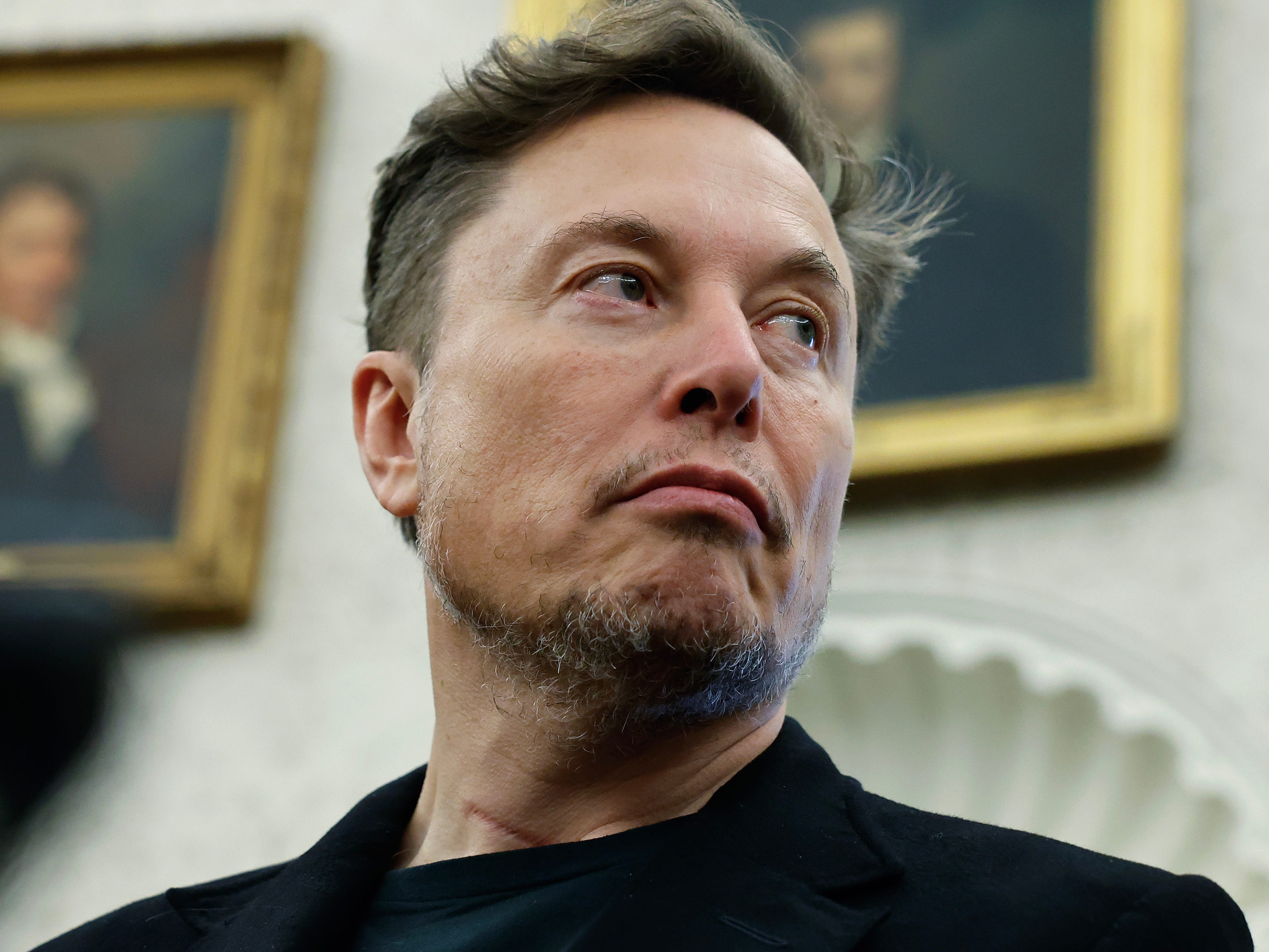 Elon Musk looks toward his right in the Oval Office at the White House.
