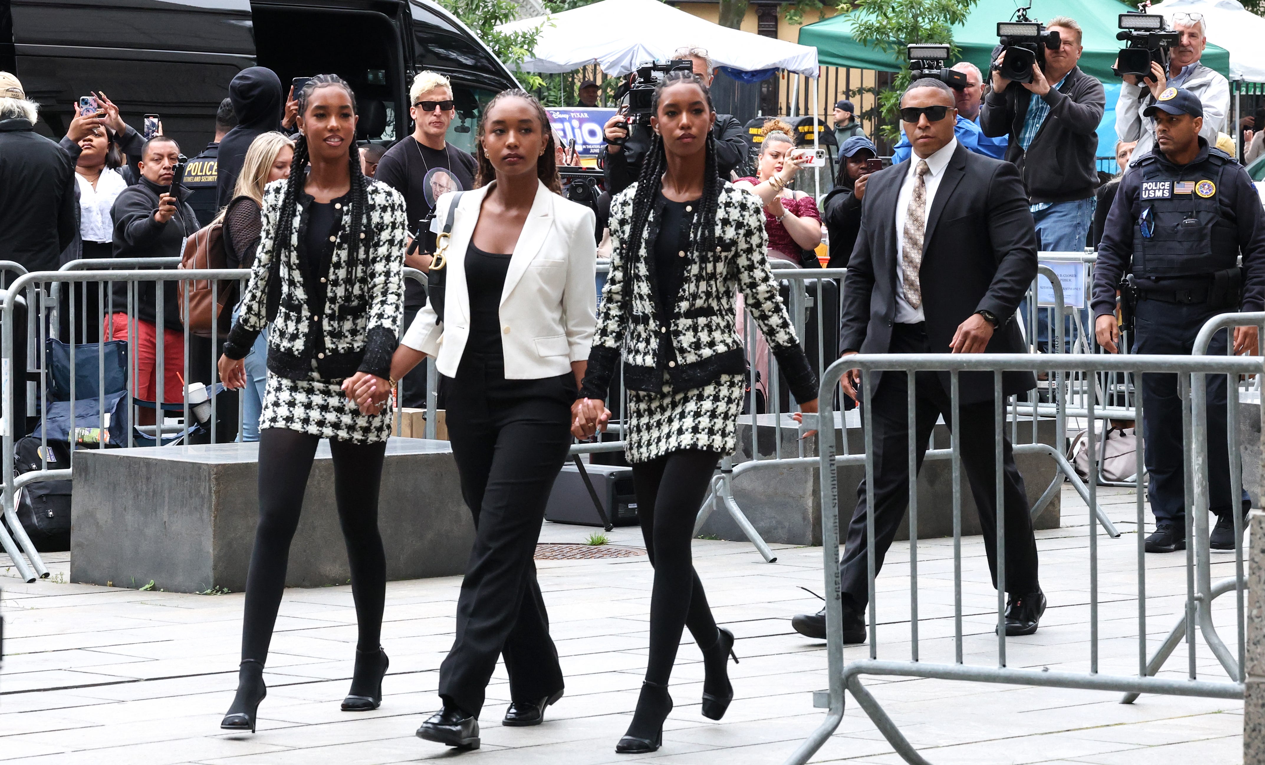 Twins D'Lila and Jessie Combs walk on either side of big sister Chance Combs as they arrive at their father's criminal trial in Manhattan.